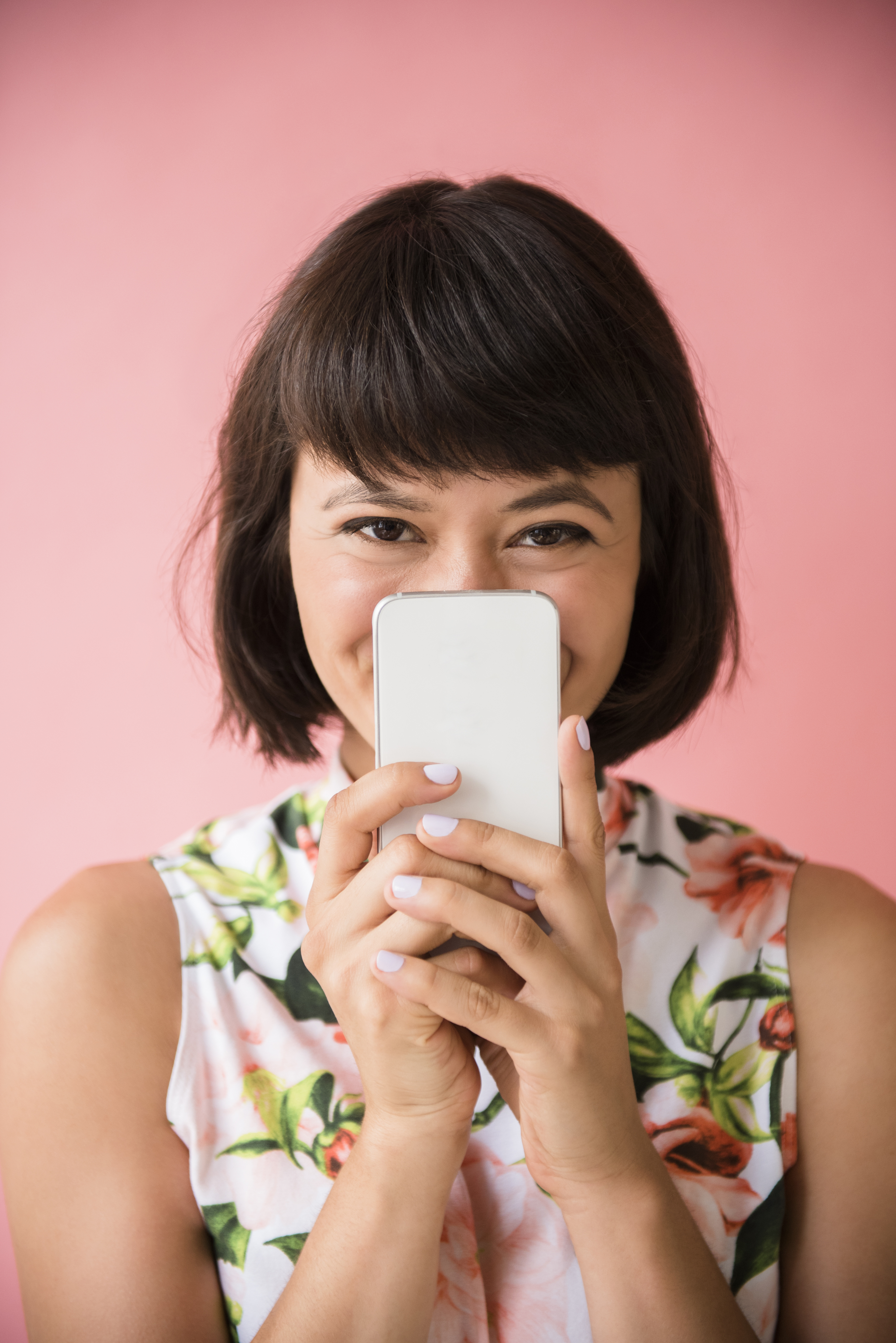 Femme hispanique cachant son visage derrière un téléphone portable | Source : Getty Images
