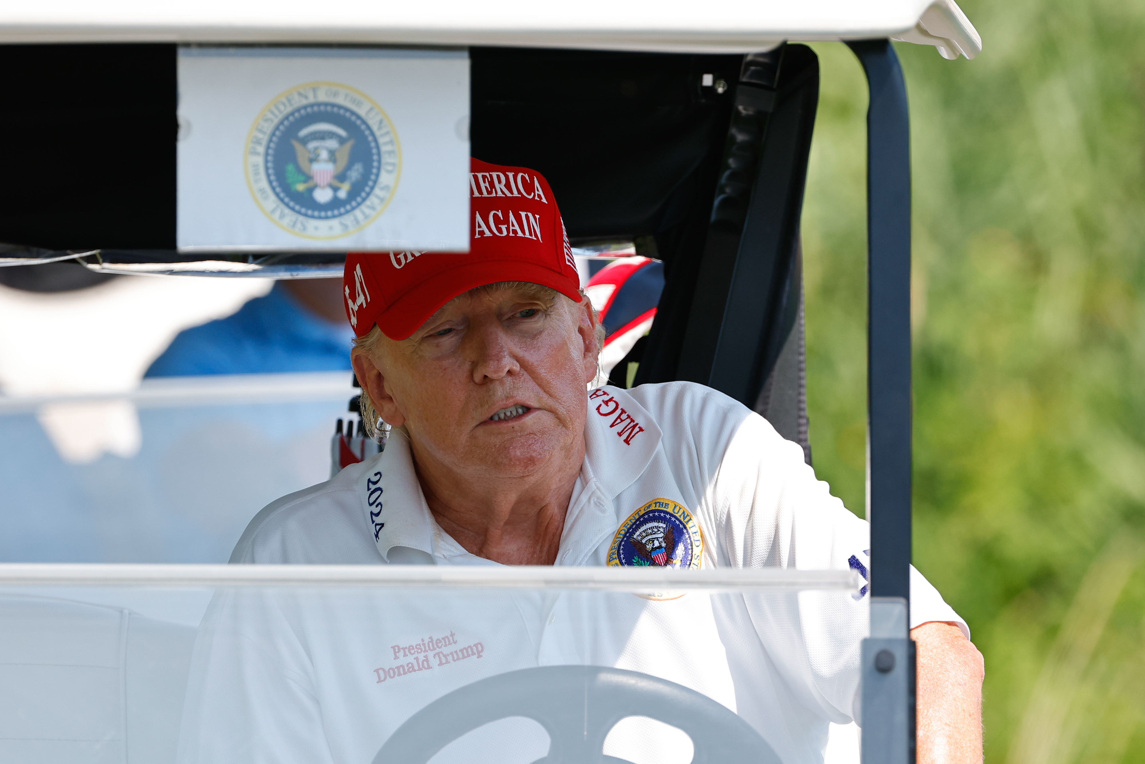 On voit le président Donald Trump conduire une voiturette de golf depuis le 15e tee pendant le tour d'entraînement au Trump National Golf Club, le 9 août 2023, à Bedminster, dans le New Jersey | Source : Getty Images