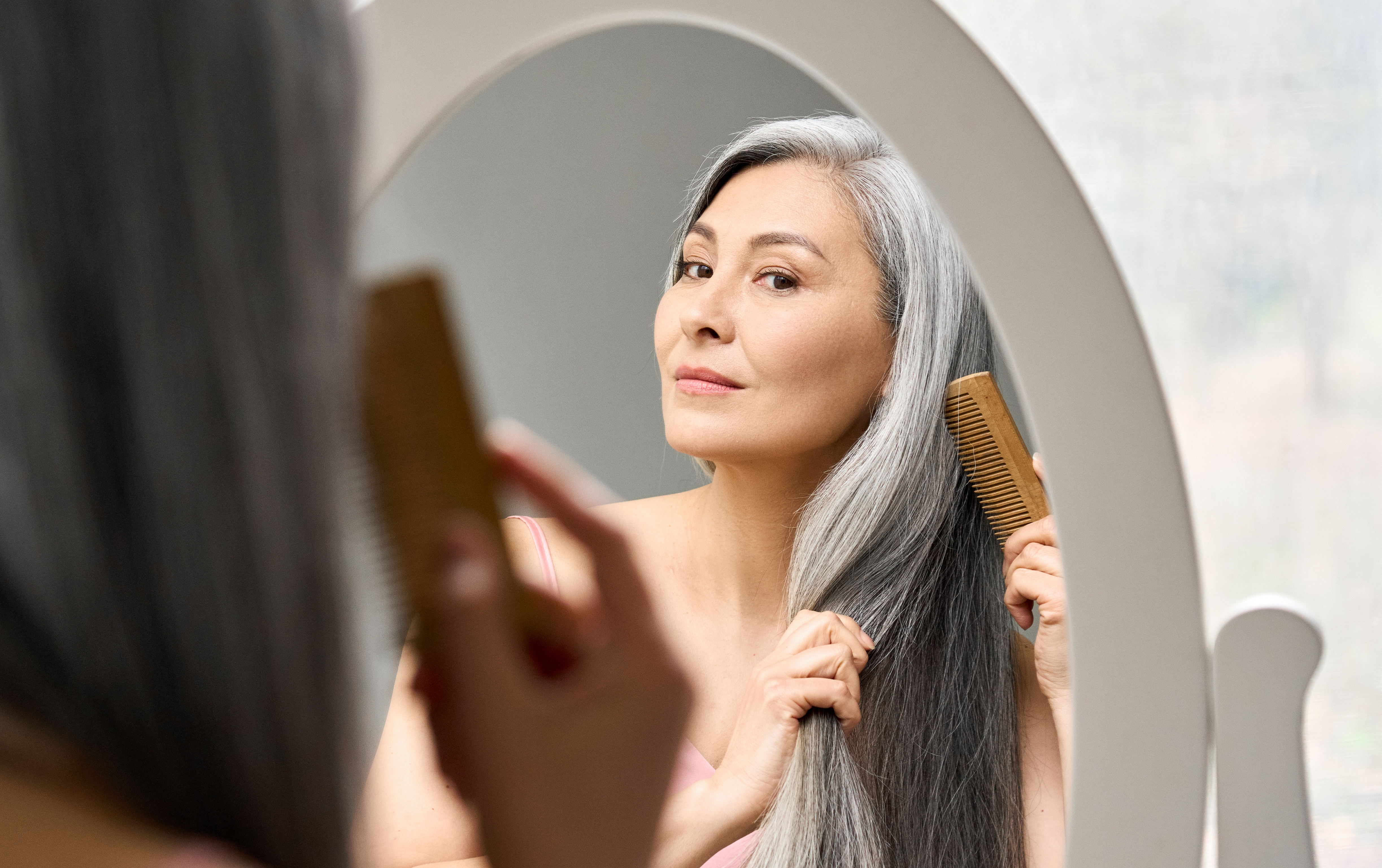 Femme aux cheveux gris peignant ses cheveux. | Source : Shutterstock