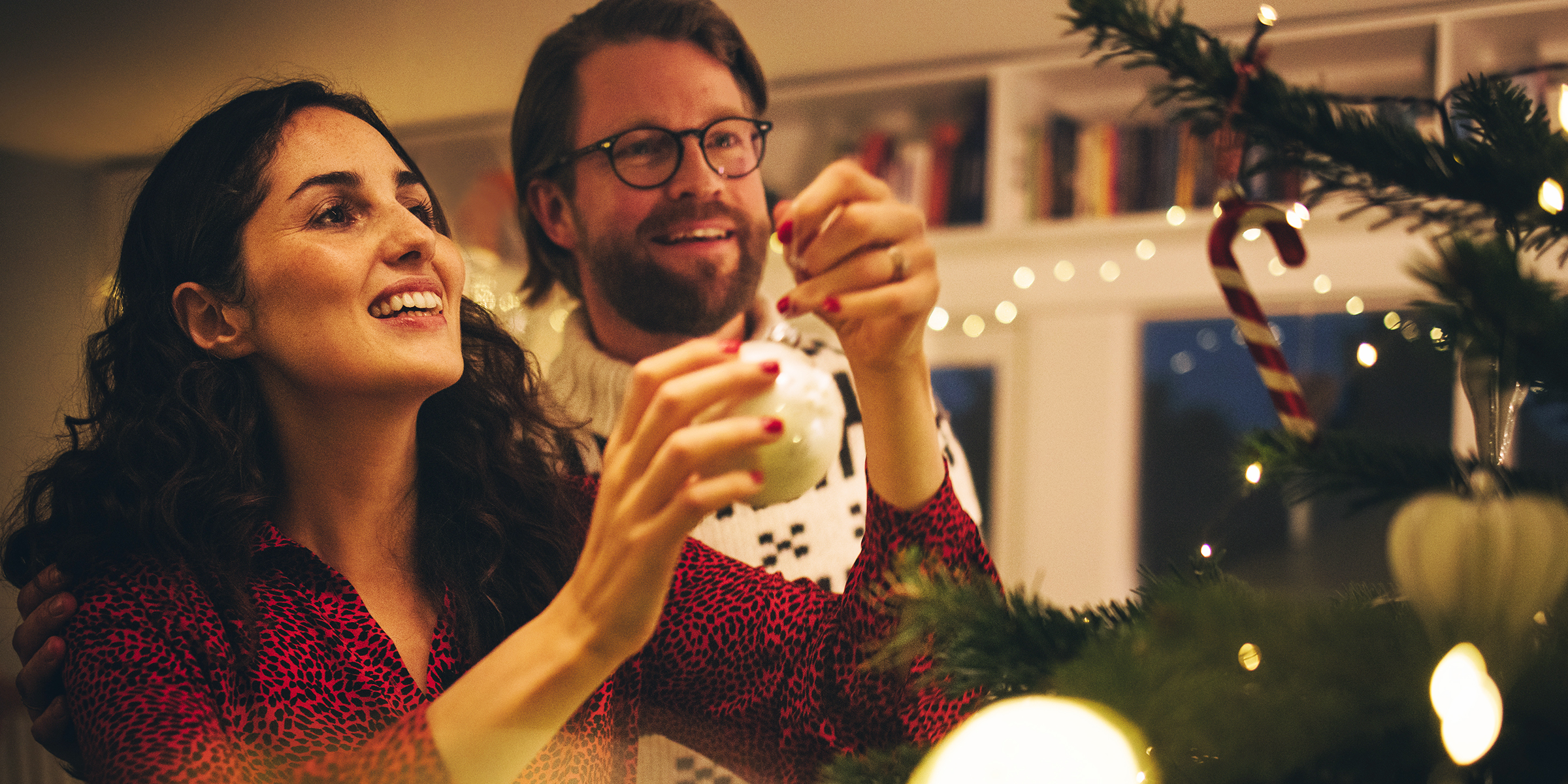 Un couple en train de décorer un sapin de Noël | Source : Shutterstock