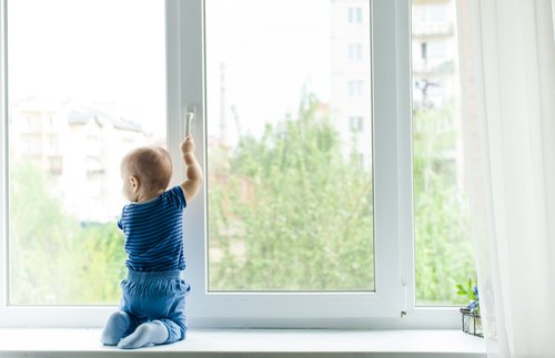 Un bébé qui s'appuie sur la fenêtre | Photo : Shutterstock