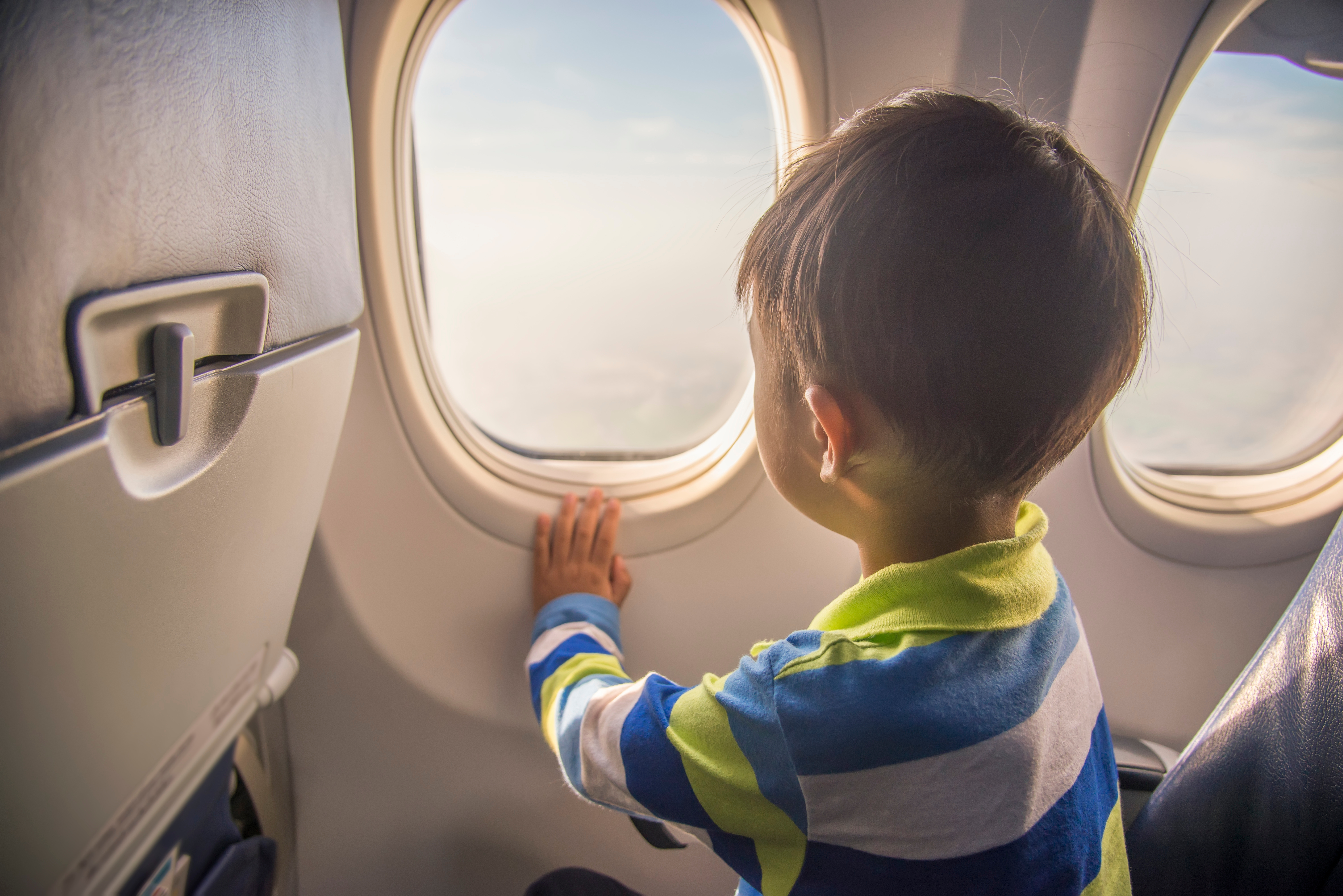 Niño mirando por la ventanilla de un avión | Fuente: Shutterstock