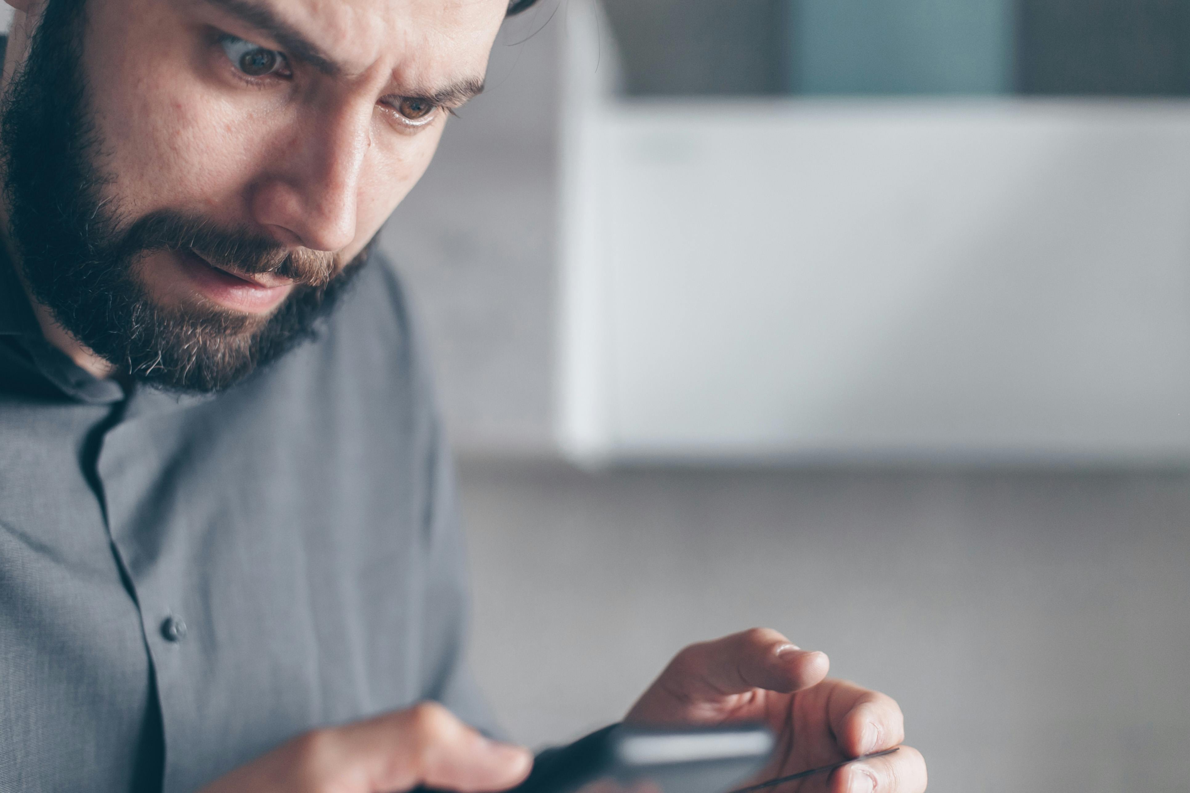 Un homme choqué qui regarde son téléphone | Source : Pexels