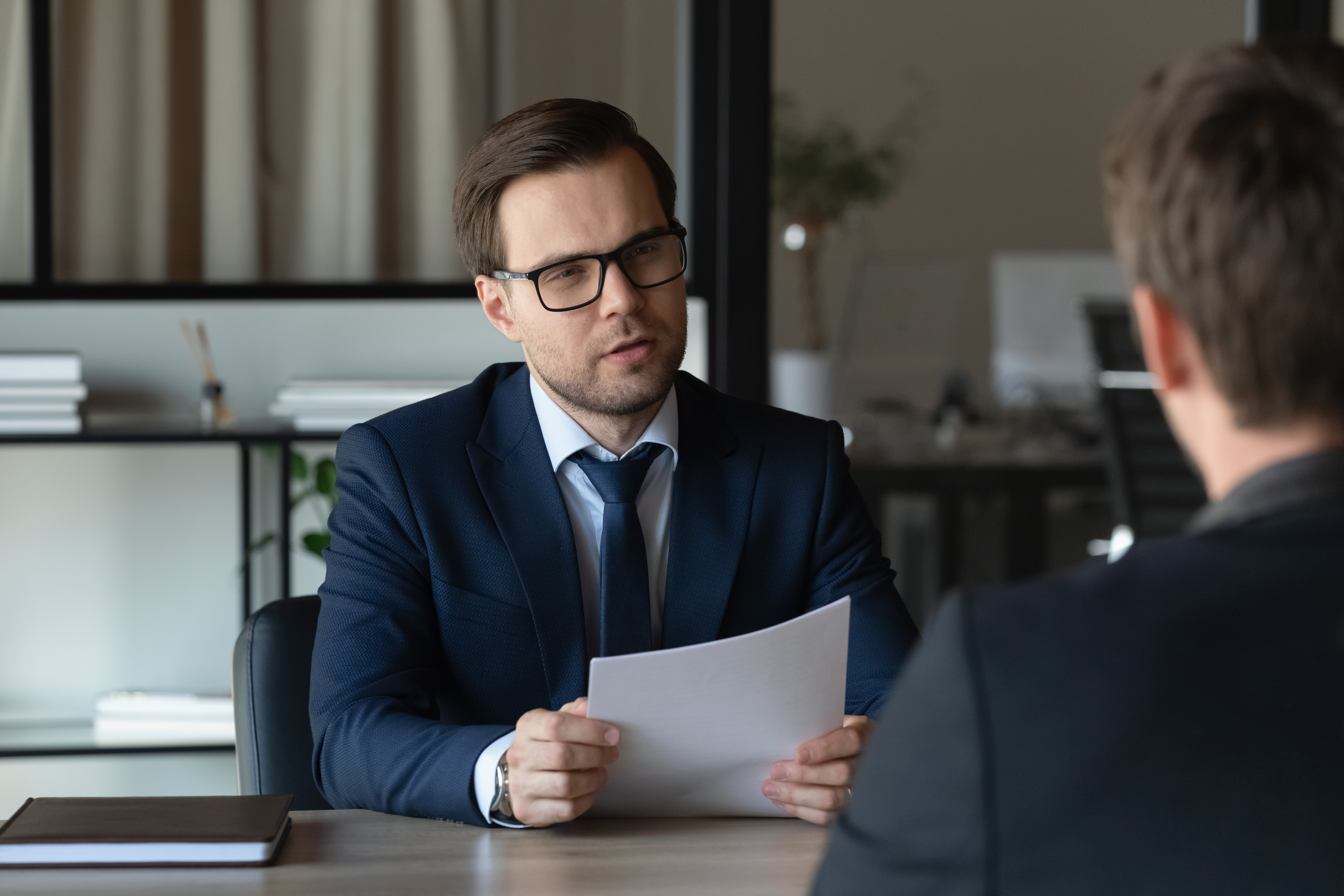 Homem sentado atrás da mesa com papéis | Fonte: Shutterstock.com