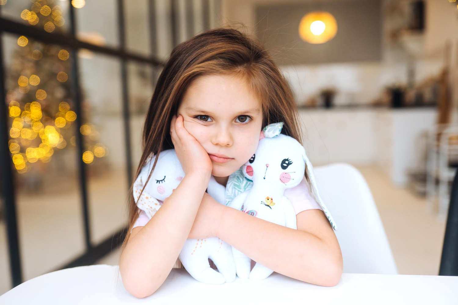 Une petite fille triste tenant ses peluches et assise dans sa chambre | Source : Freepik