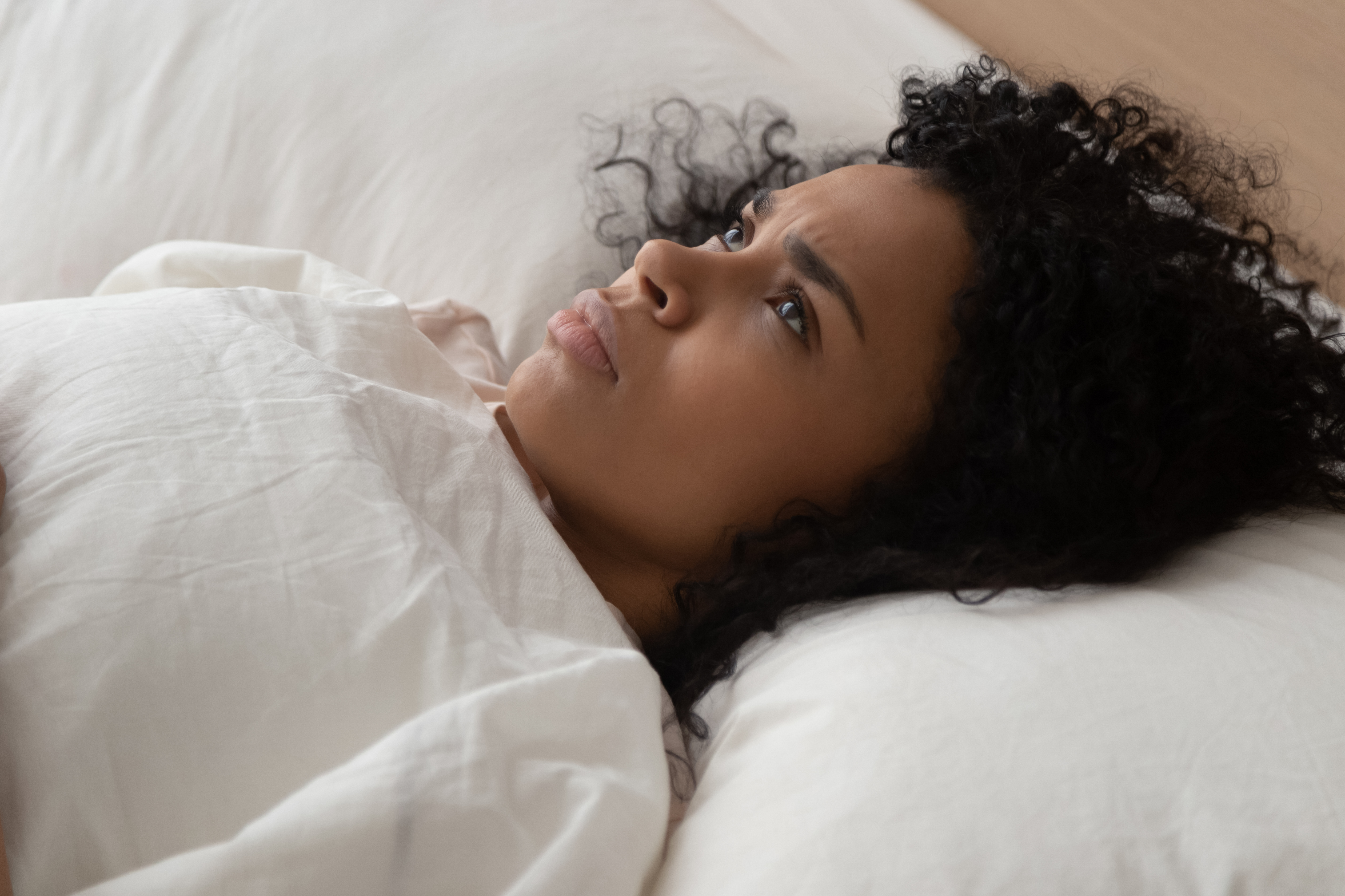 Une femme noire regardant le plafond alors qu'elle a du mal à s'endormir | Source : Shutterstock