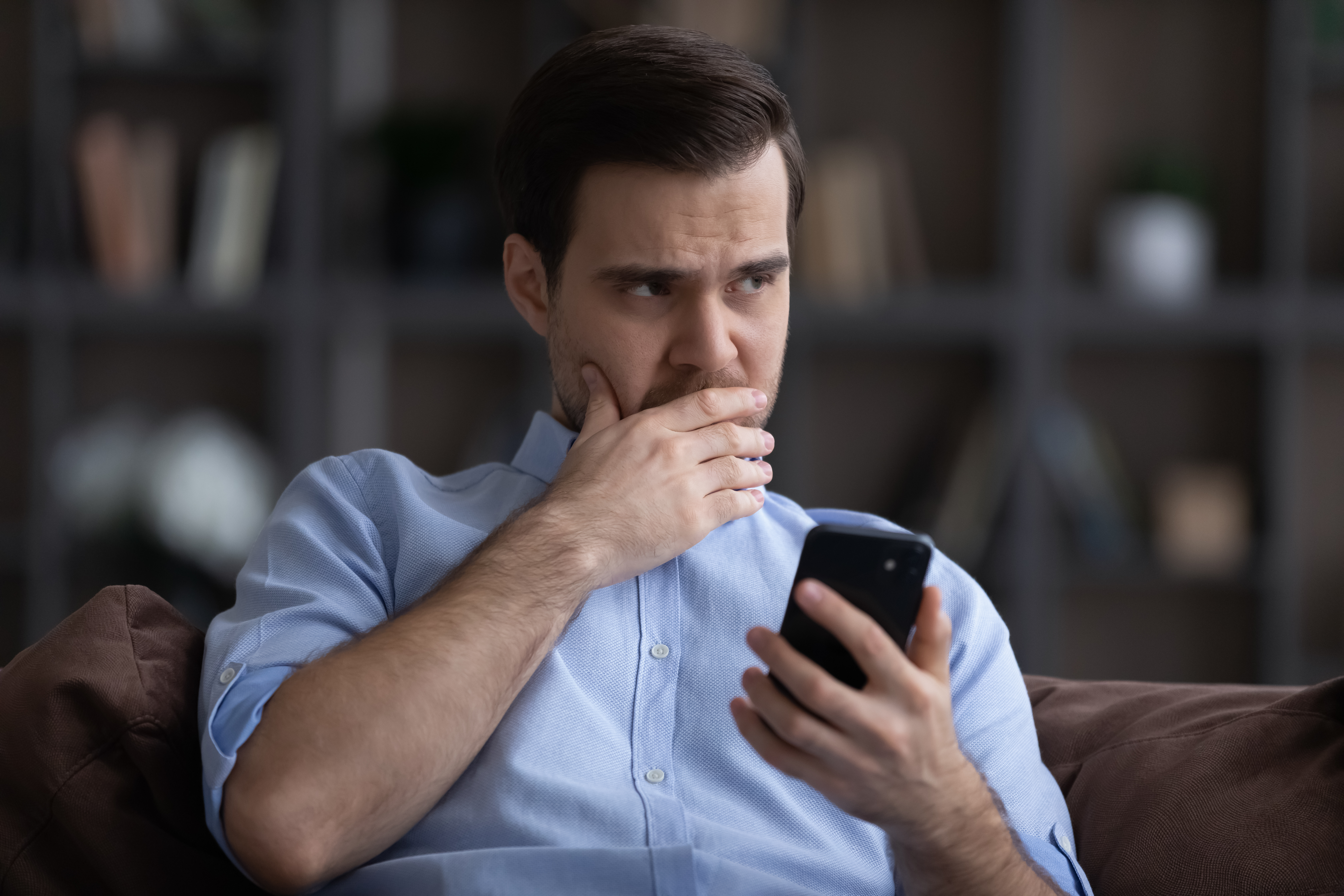 Un homme en détresse tenant un smartphone | Source : Shutterstock