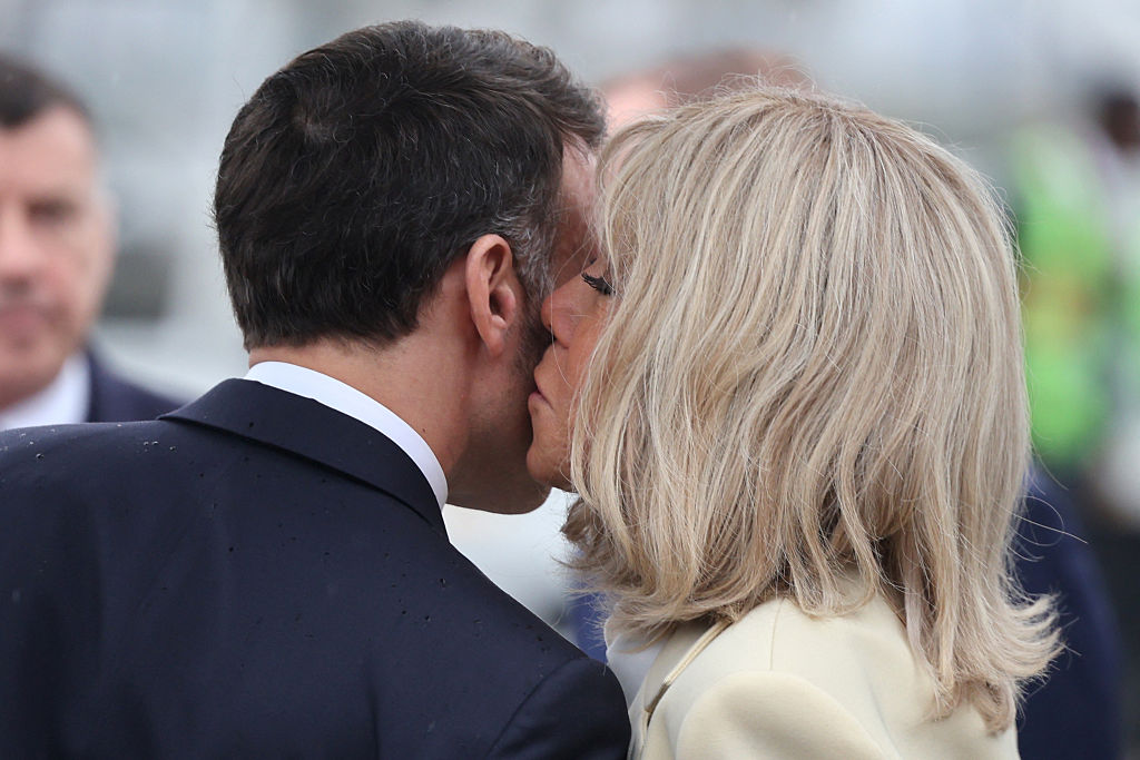 Le président français Emmanuel Macron (à gauche) reçoit un baiser de son épouse Brigitte Macron (à droite) avant de partir chacun de leur côté pour leur visite, après leur arrivée à New Delhi le 18 février 2026 I Source : Getty Images