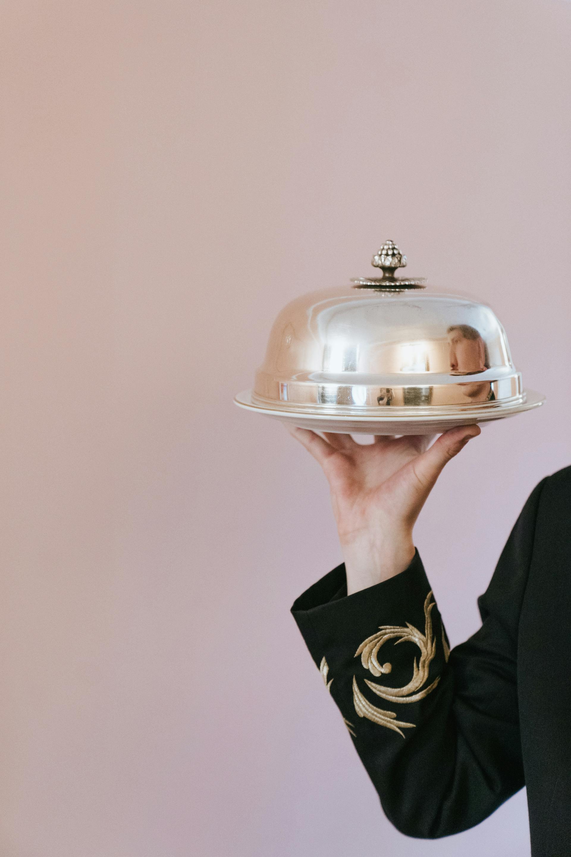 Une personne tenant un plat recouvert d'une cloche | Source : Pexels