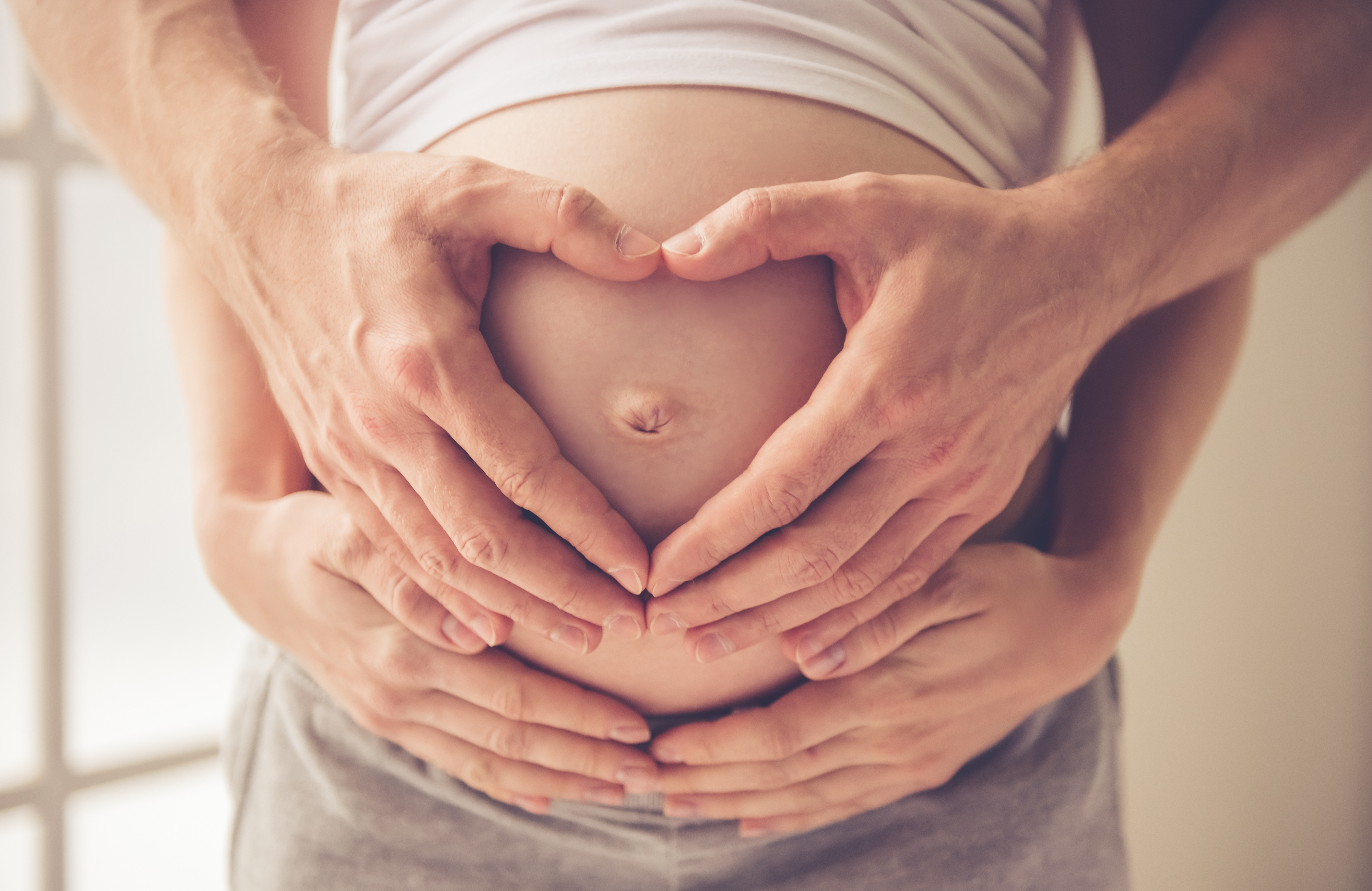 Un couple tenant un ventre de femme enceinte | Source : Shutterstock