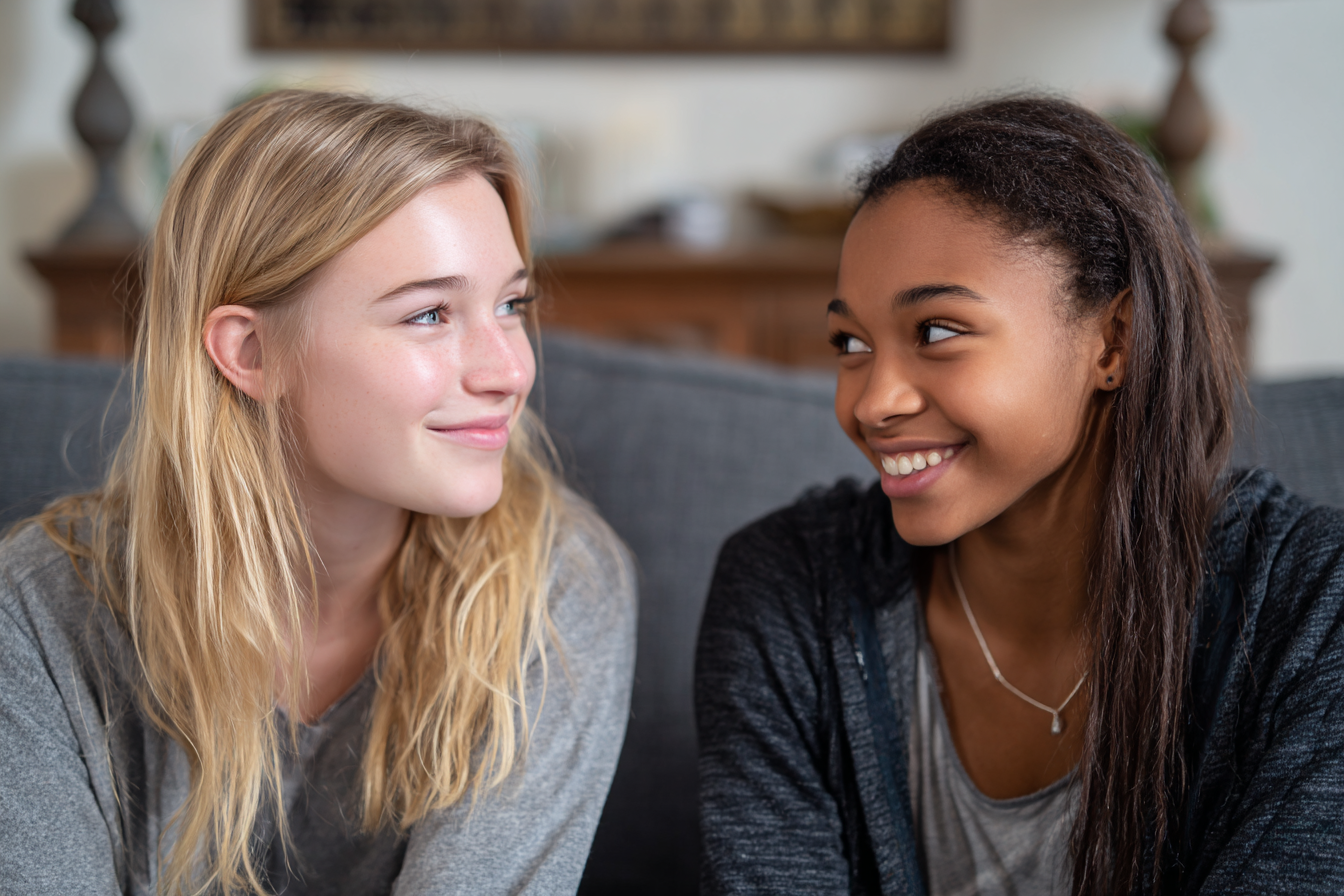 Deux adolescentes se sourient sur un canapé | Source : Midjourney