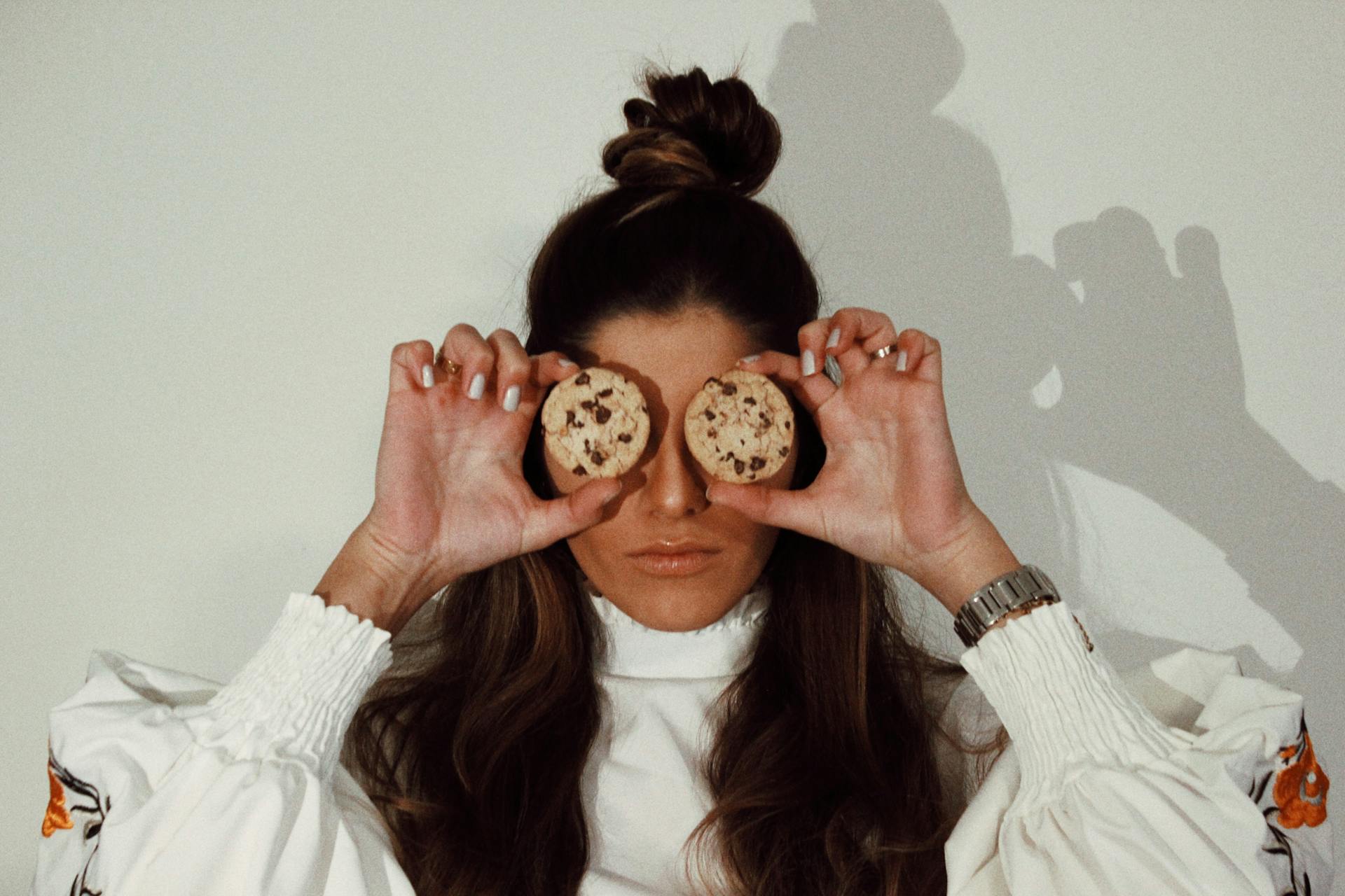 Une femme se couvrant les yeux avec deux biscuits aux pépites de chocolat | Source : Pexels