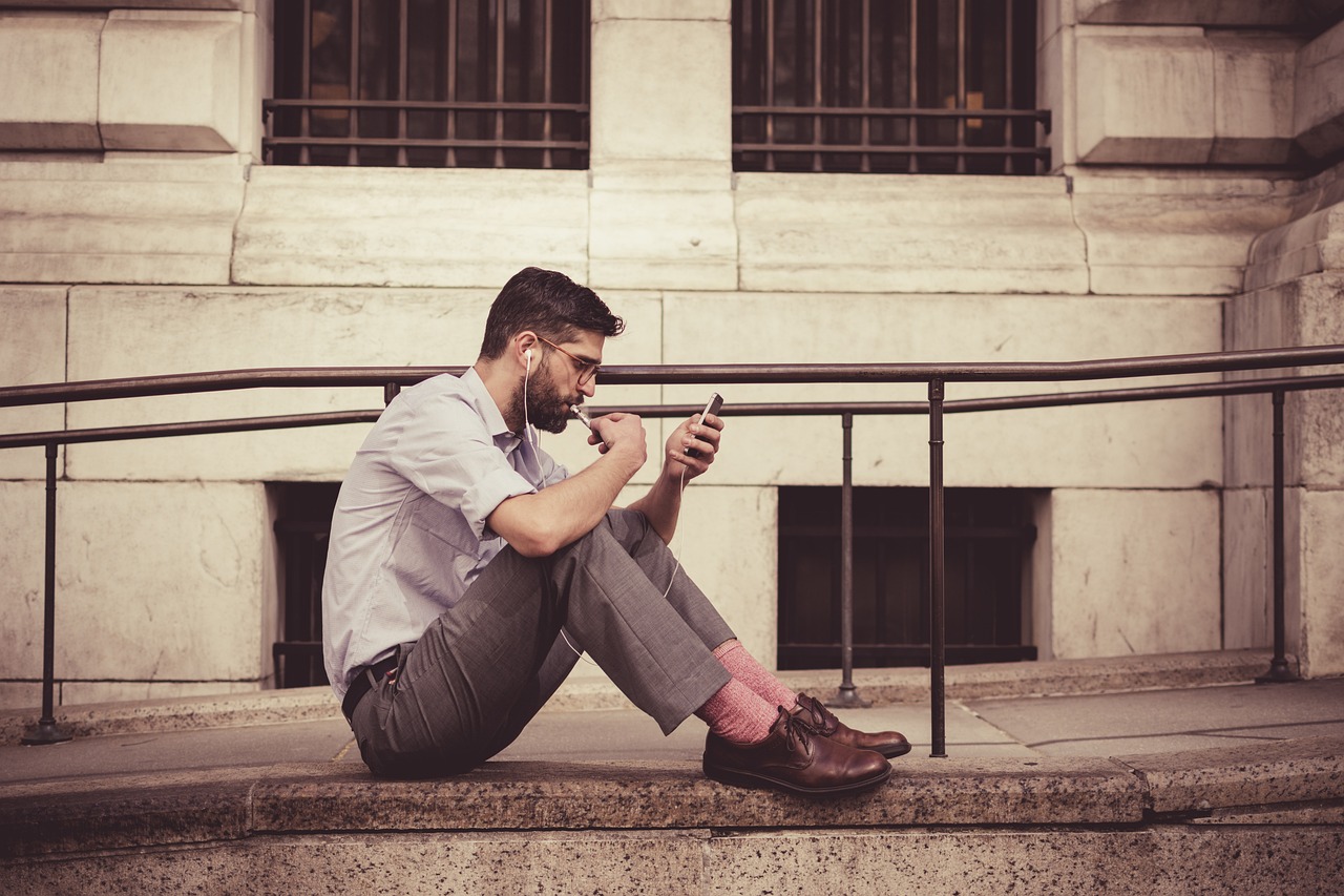 Un homme assis par terre en train de parler au téléphone | Source : Pixabay
