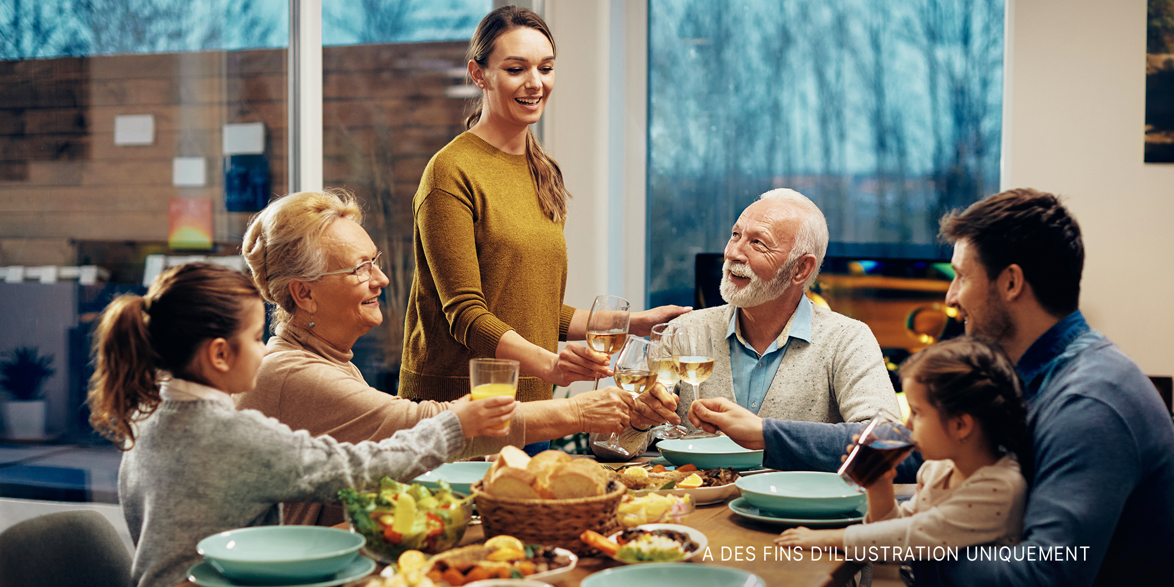 Une famille élargie, heureuse de porter un toast tout en déjeunant ensemble dans la salle à manger | Source : Shutterstock