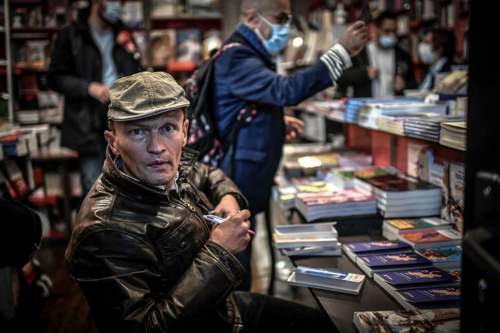 L'écrivain français Sylvain Tesson pose à l'intérieur de la Librairie des Abbesses, dans le quartier de Montmartre, alors qu'il dédicace un de ses livres lors du lancement de l'événement "Rallumez les feux de nos librairies" le 2 novembre 2020 à Paris. | Photo : Getty Images