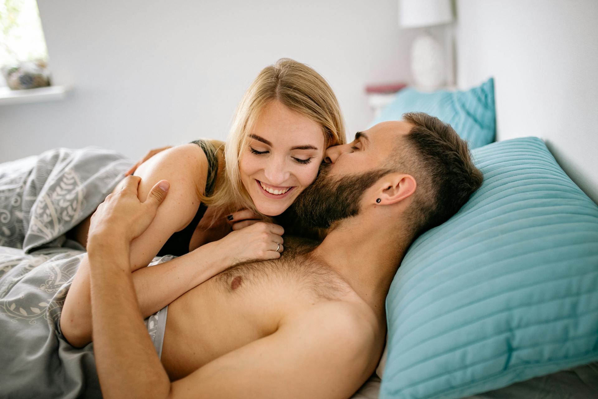 Un homme embrassant une femme au lit | Source : Pexels