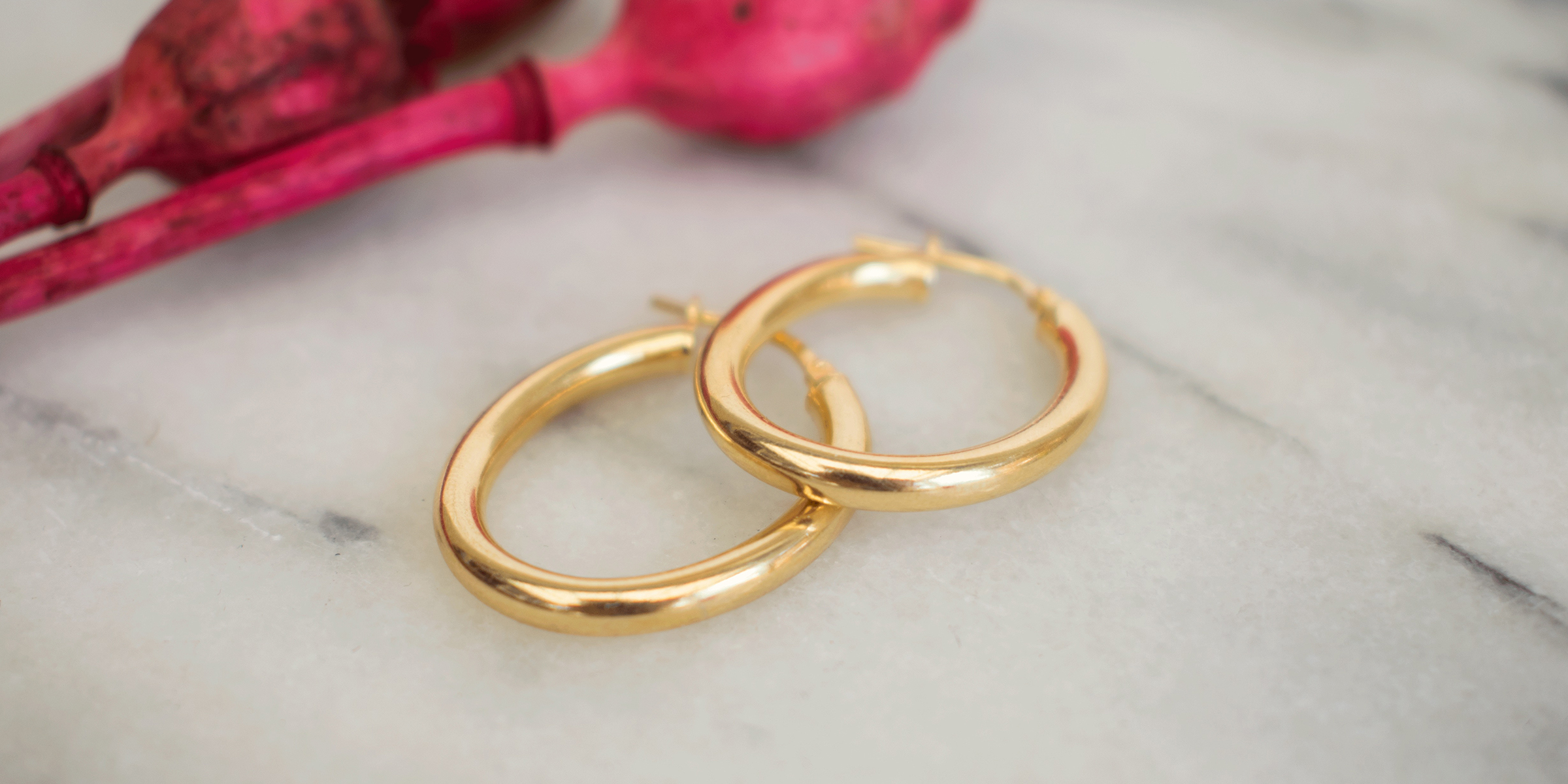 Une paire de boucles d'oreilles en or sur une surface en marbre | Source : Shutterstock