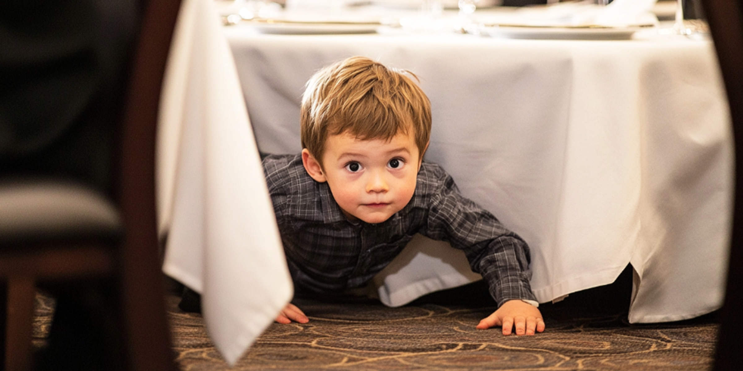 Un enfant qui joue en rampant sous une table | Source : The Celebritist