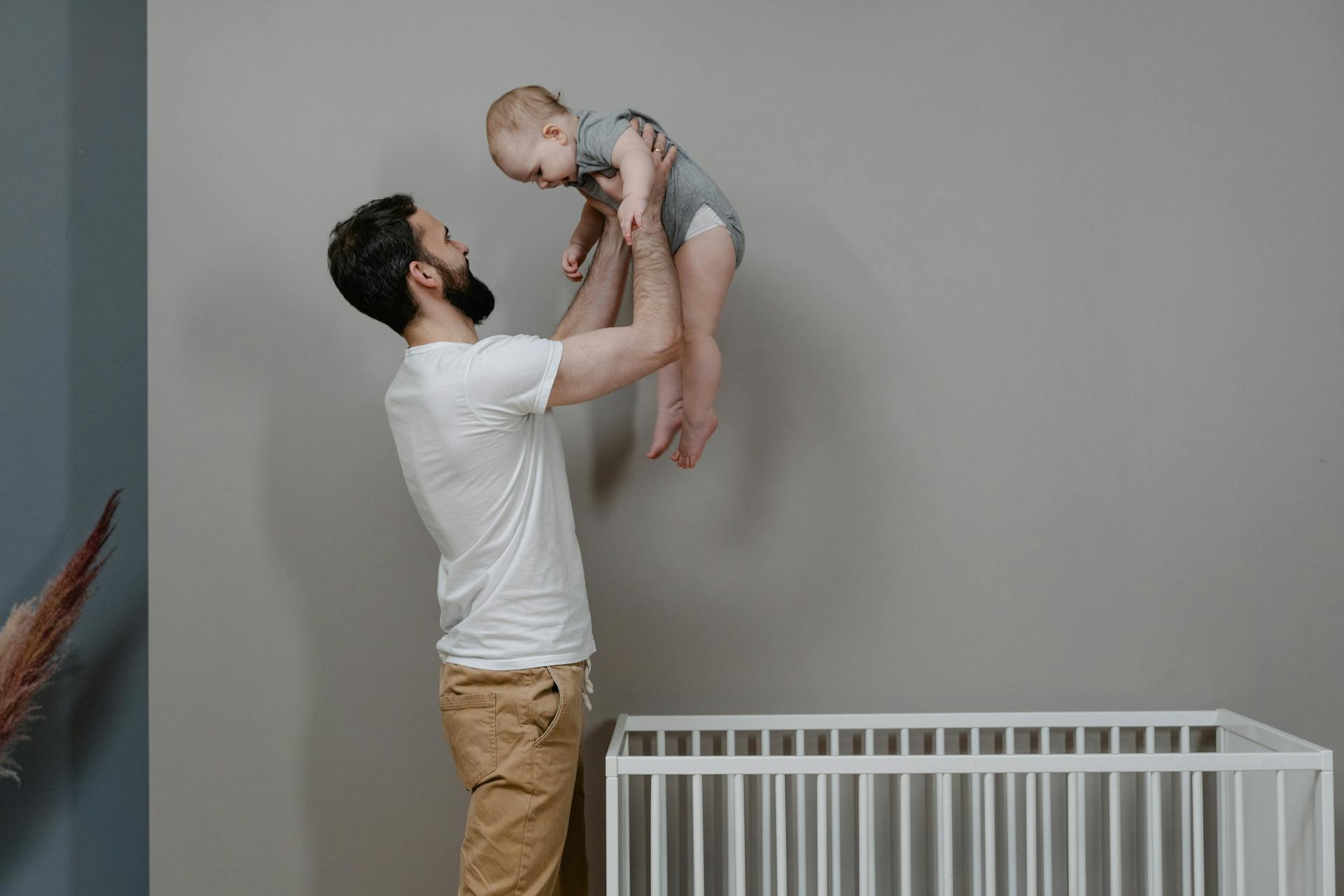 Un homme soulève un bébé hors d'un berceau | Source : Pexels