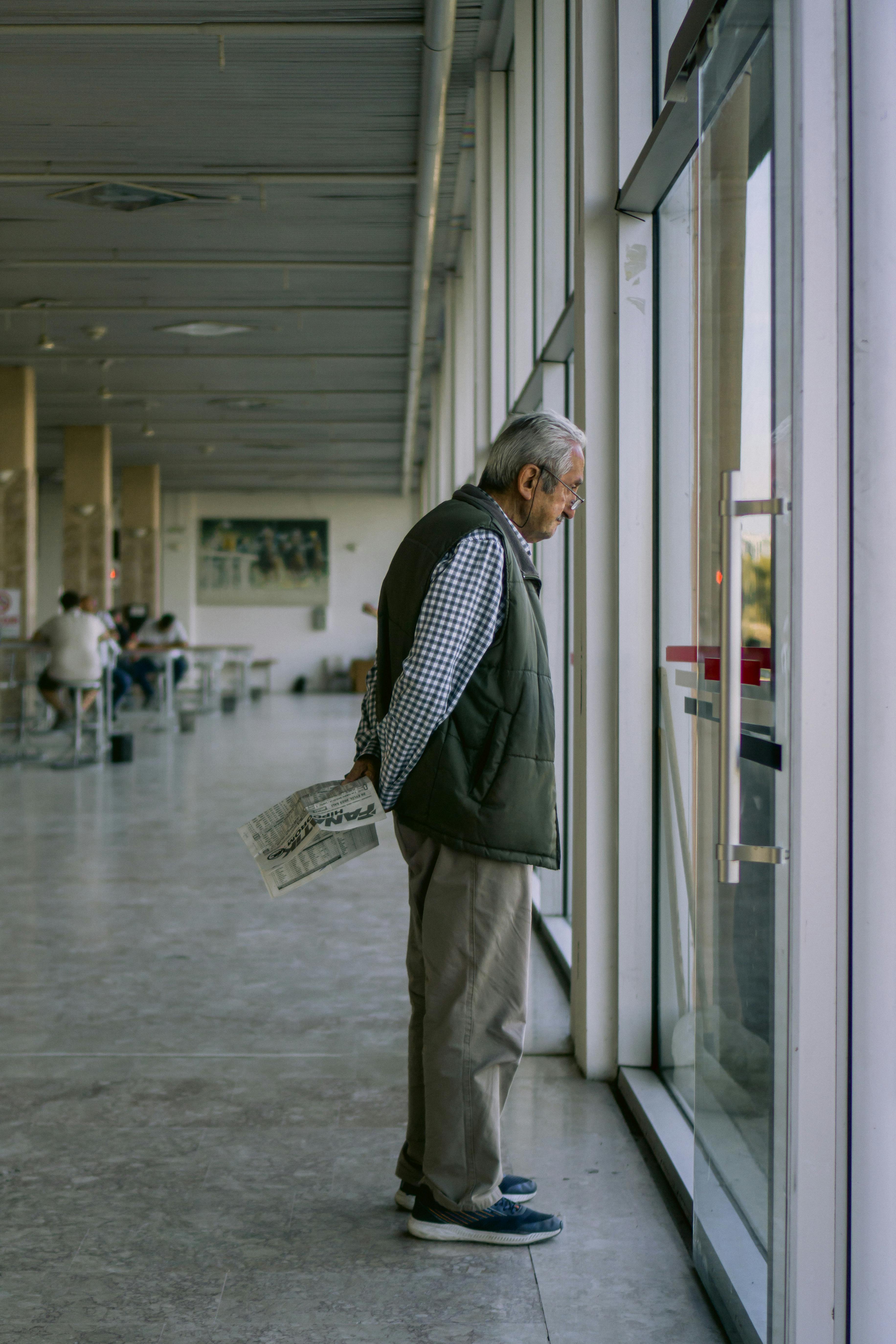 Un homme âgé regardant par la fenêtre dans un aéroport | Source : Pexels