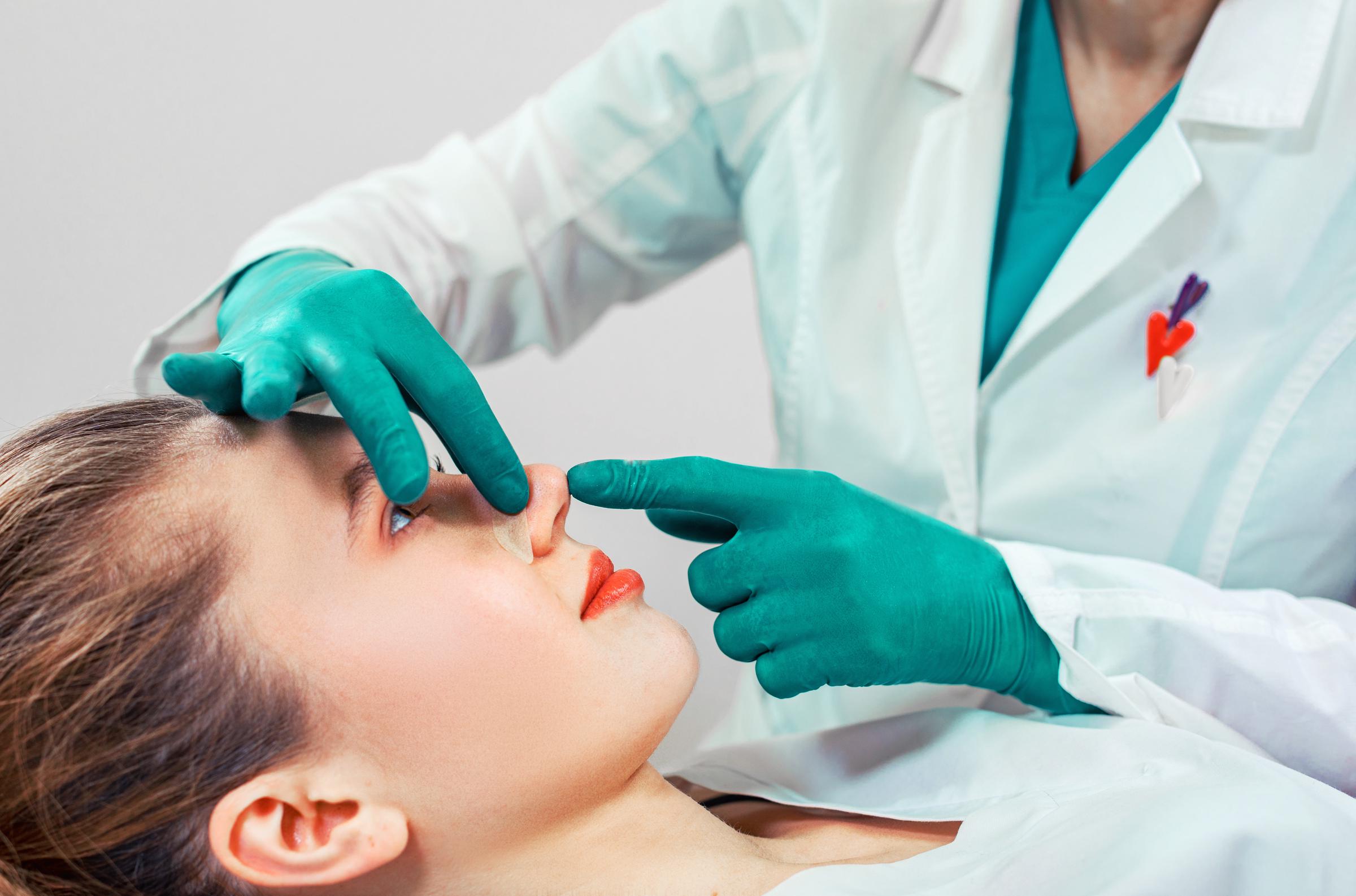 Les mains du cosmétologue touchent le nez du patient | Source : Getty images