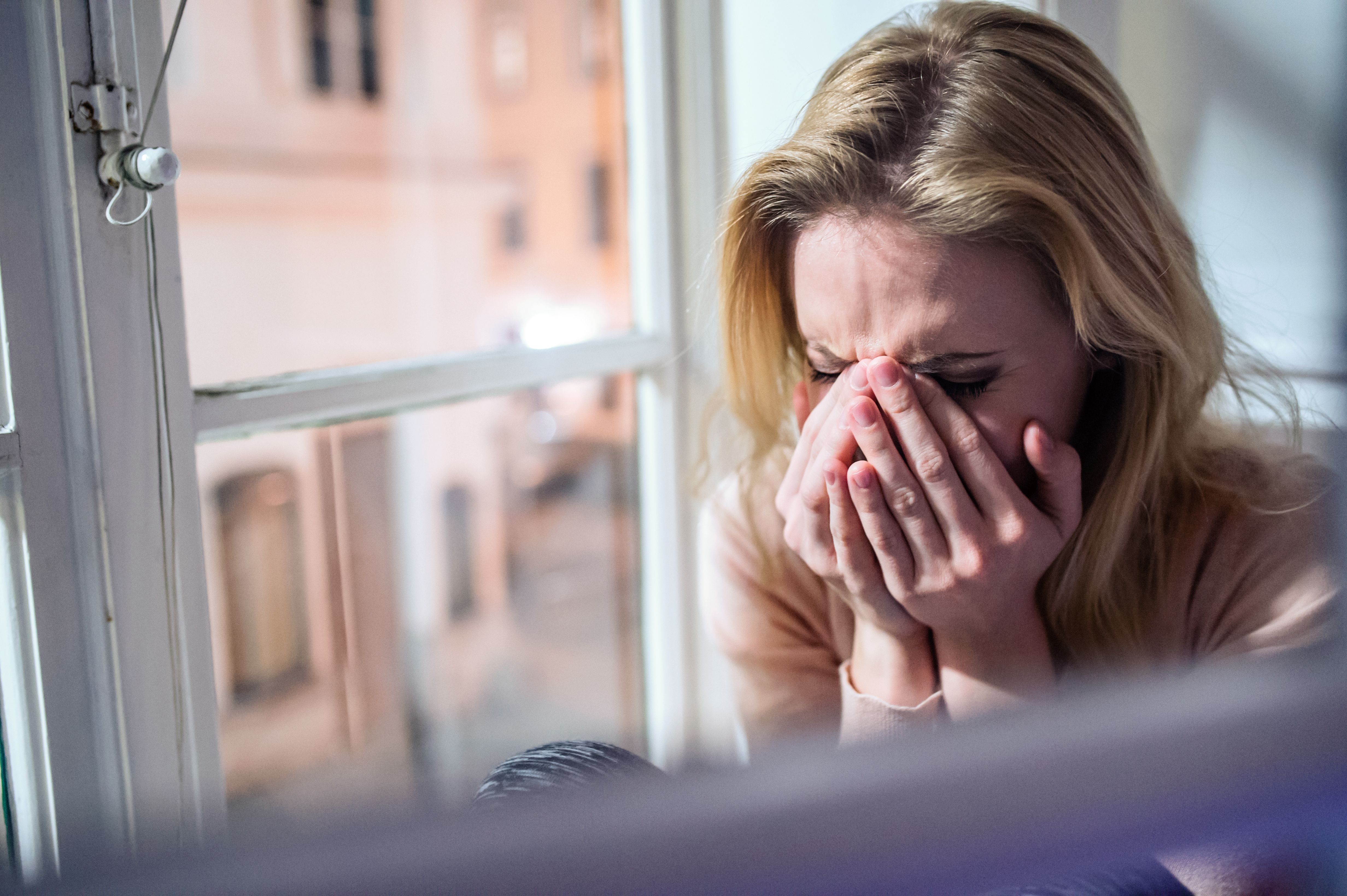 Une femme qui pleure, assise près de la fenêtre | Source : Shutterstock