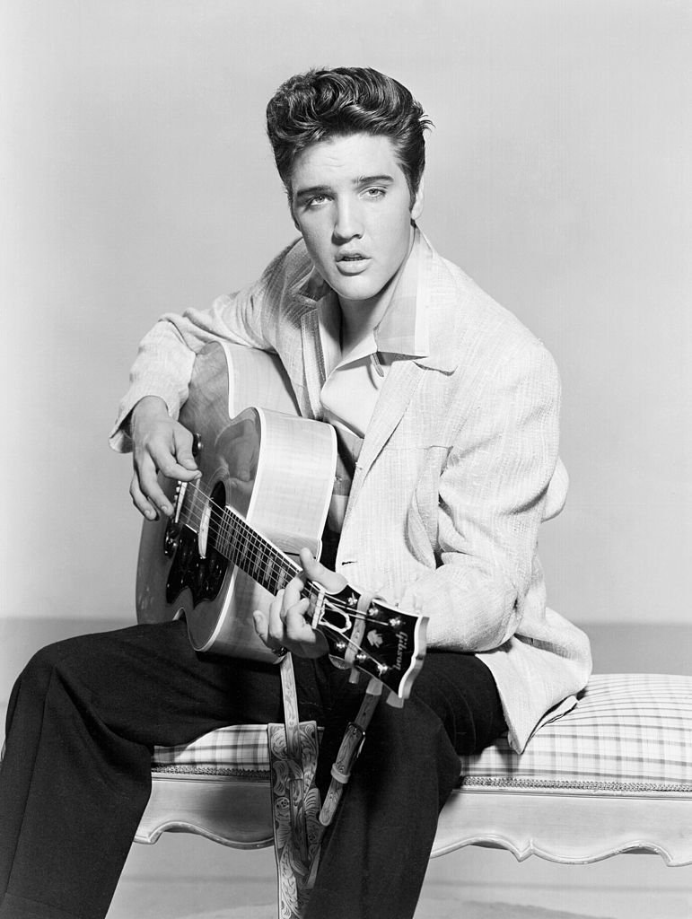 Elvis Presley gratte sa guitare acoustique dans un portrait en 1956 | Photo : Getty Images