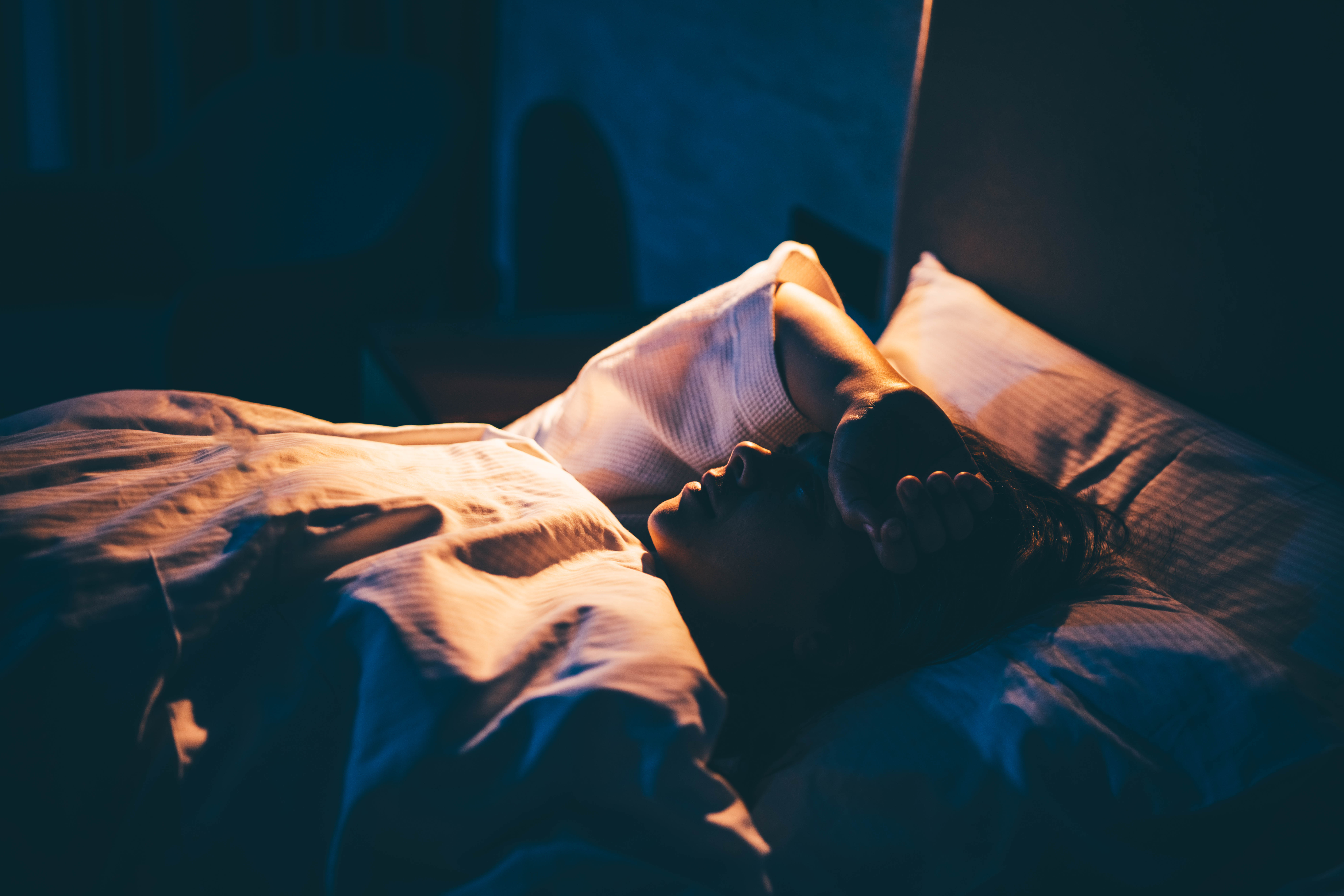 Femme souffrant d'insomnie. Jeune femme allongée sur le lit, la main sur le front | Source : Getty Images