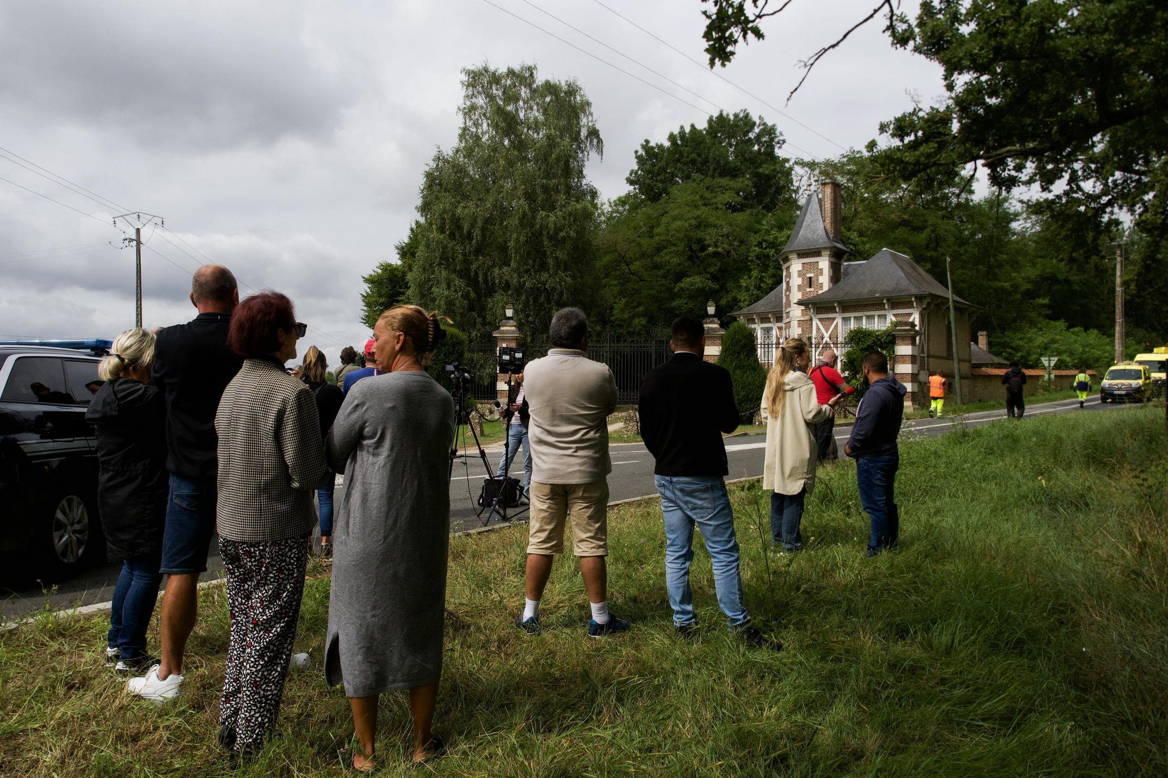 Des habitants rendent hommage alors que des journalistes travaillent devant l'entrée de la propriété d'Alain Delon, La Brulerie, à Douchy, dans le centre de la France, le 18 août 2024.