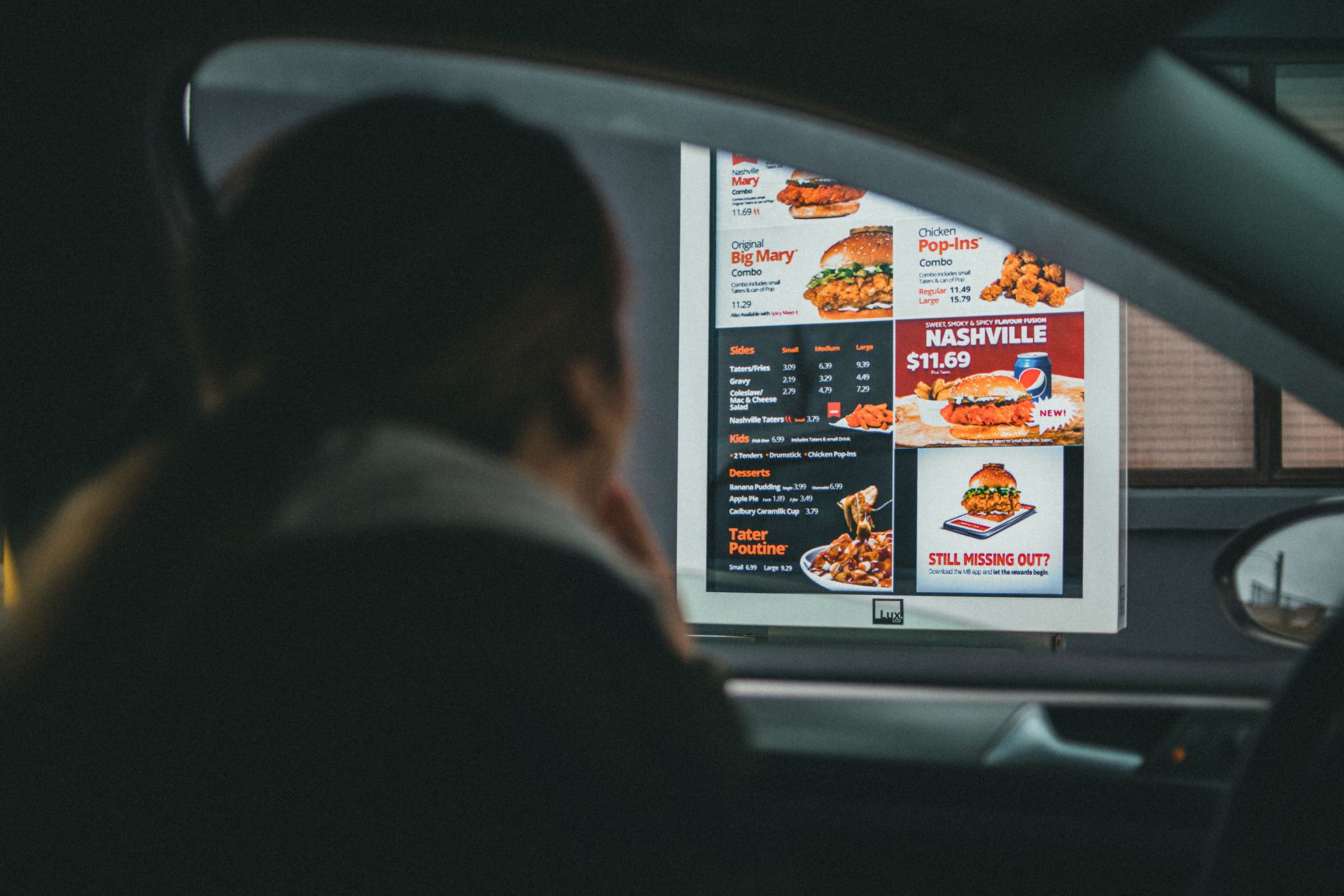 Une femme dans une voiture en train de regarder le menu d'un fast-food | Source : Pexels