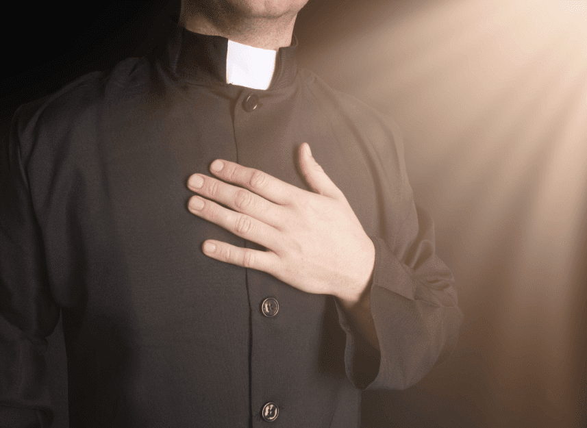 un homme d'église main sur le cœur | Photo : Shutterstock