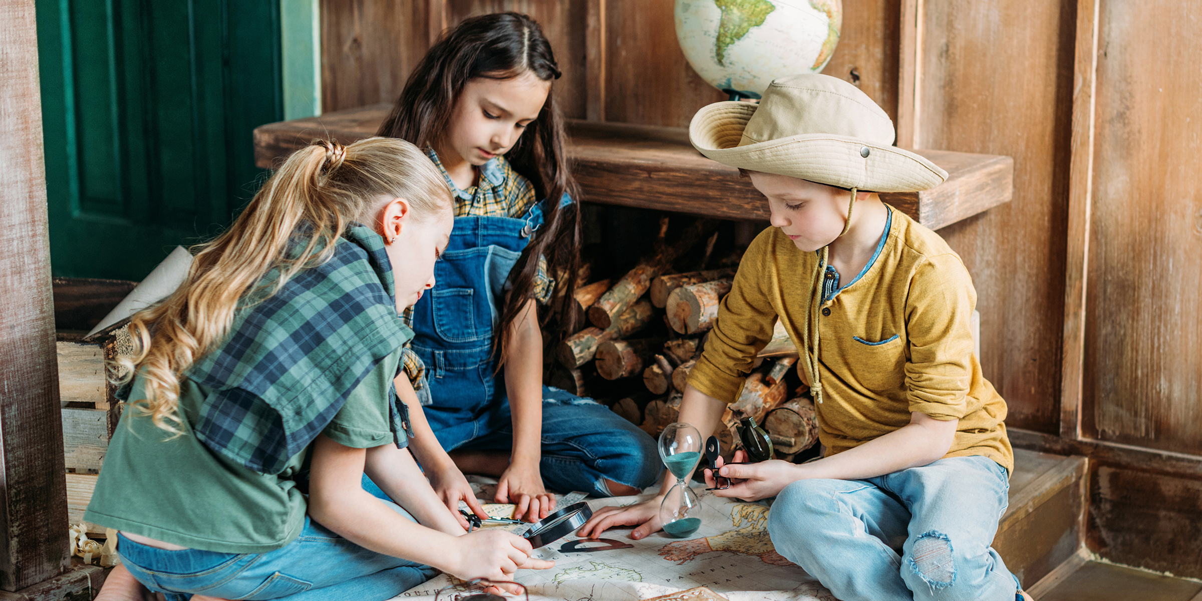 Trois enfants jouant avec une carte | Source : Shutterstock