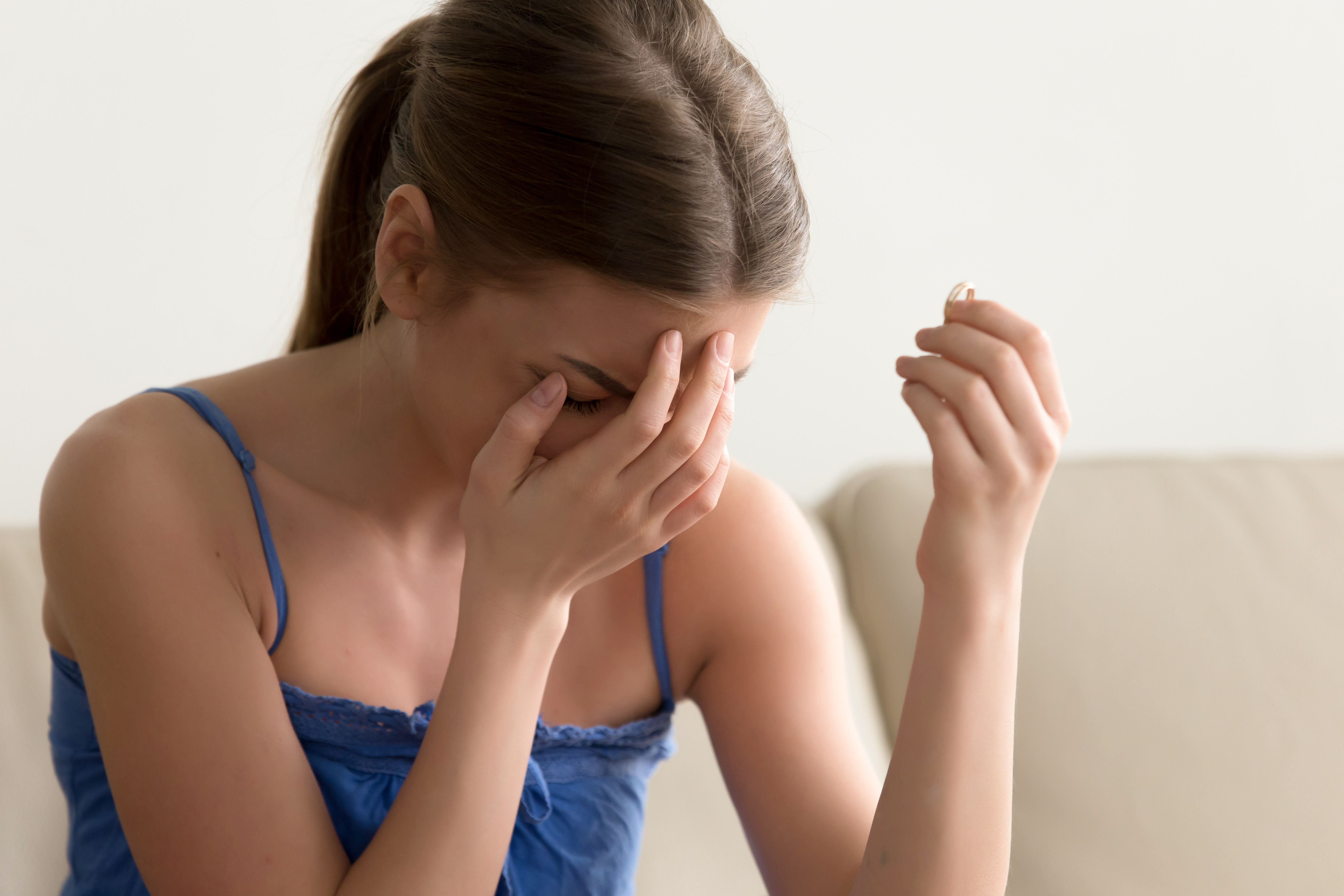 Femme qui pleure en tenant sa bague de fiançailles | Source : Shutterstock