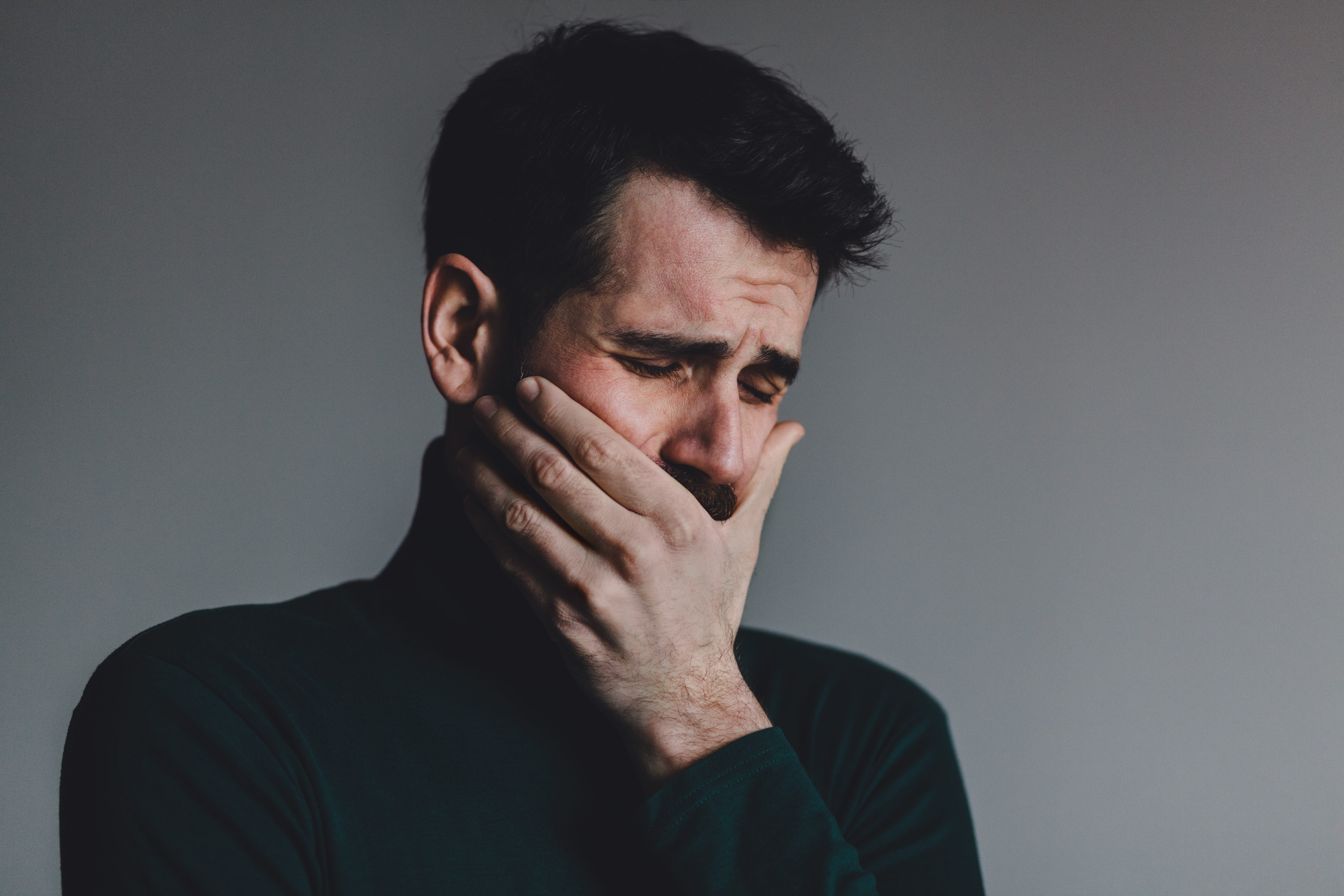 Un homme se tenant la bouche alors qu'il pleure | Source : Shutterstock