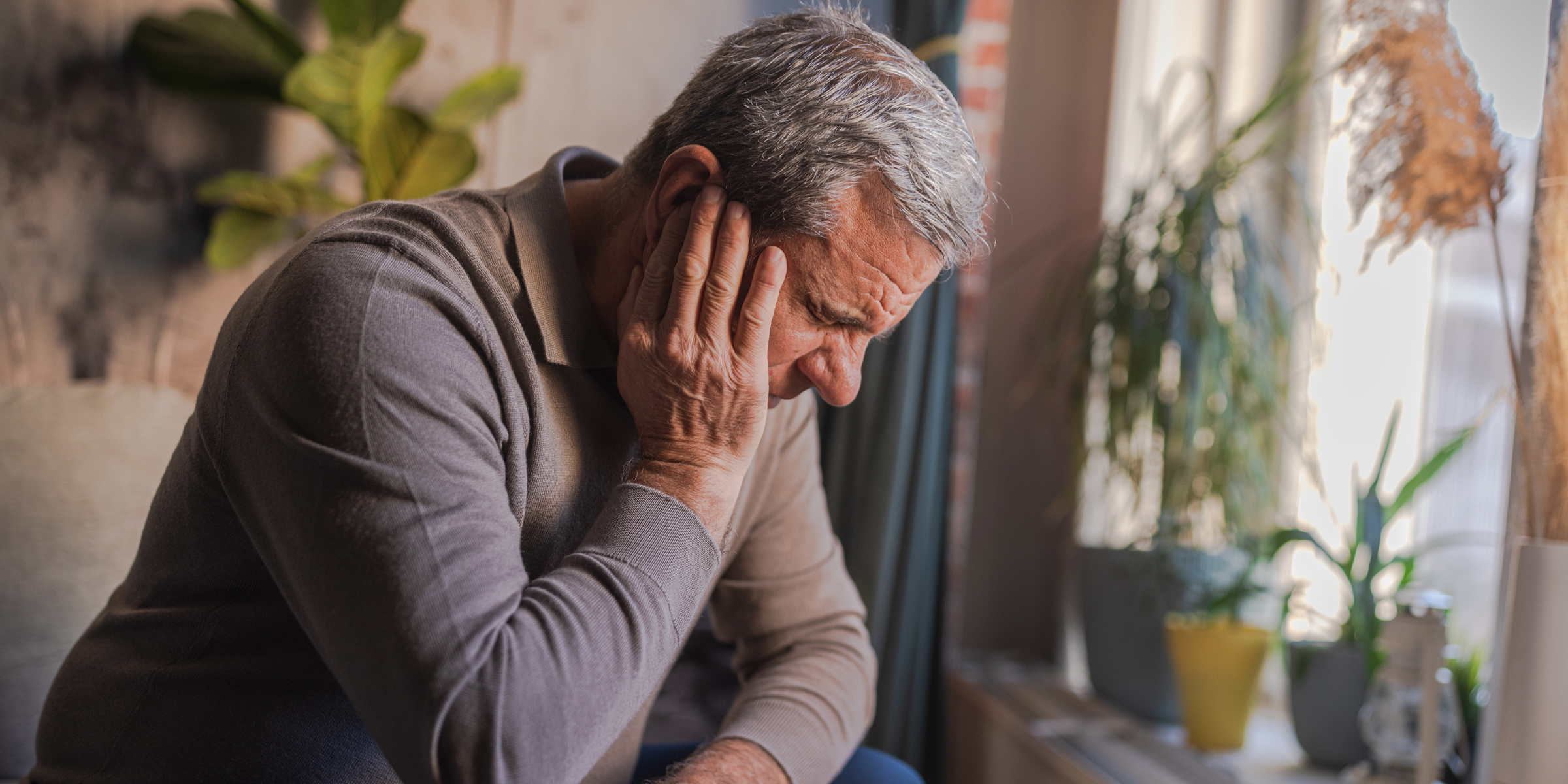 Un homme grimace de douleur à cause d'un mal d'oreille sévère | Source : Getty Images