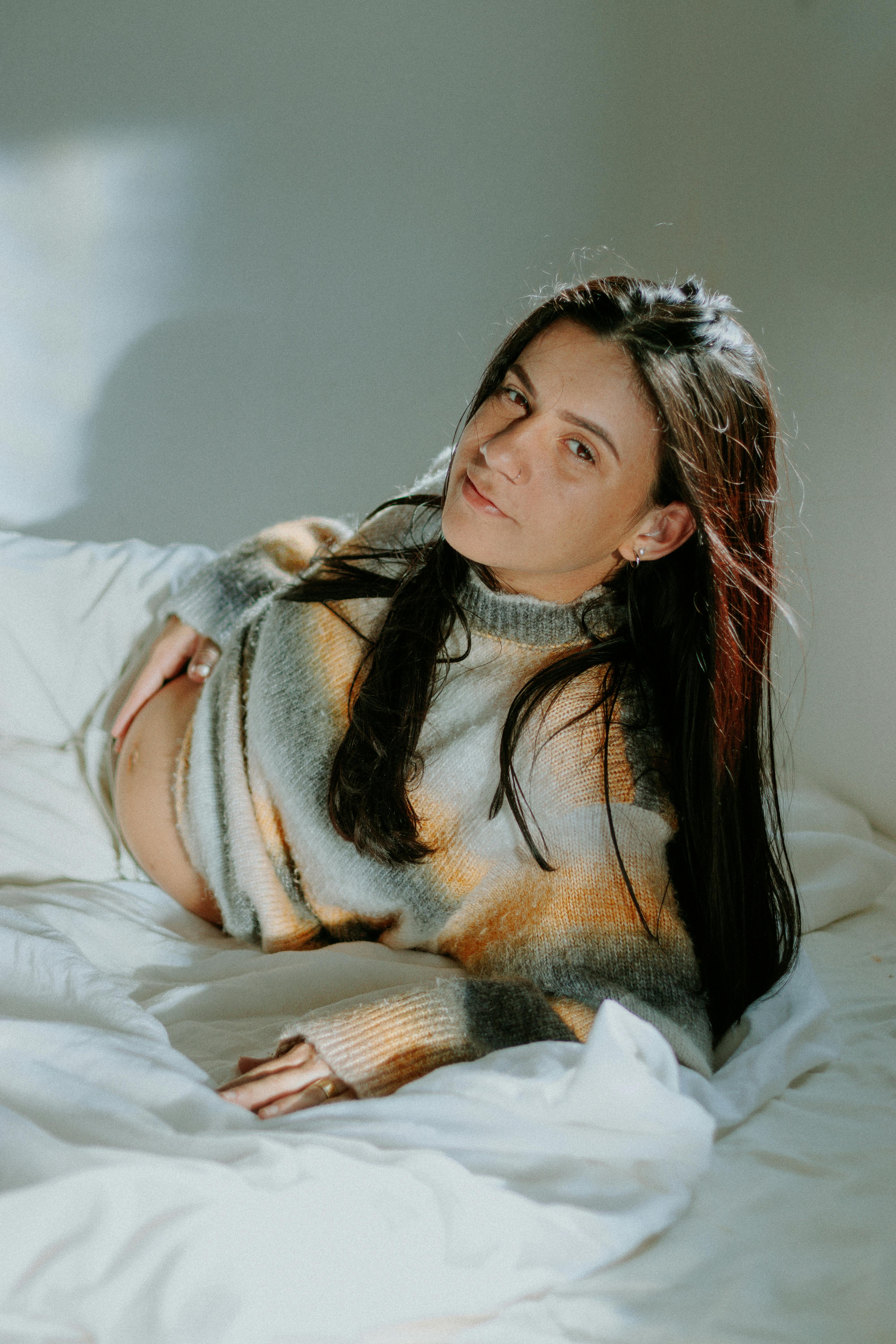 Une femme enceinte a l'air mécontente alors qu'elle est allongée sur un lit | Source : Pexels