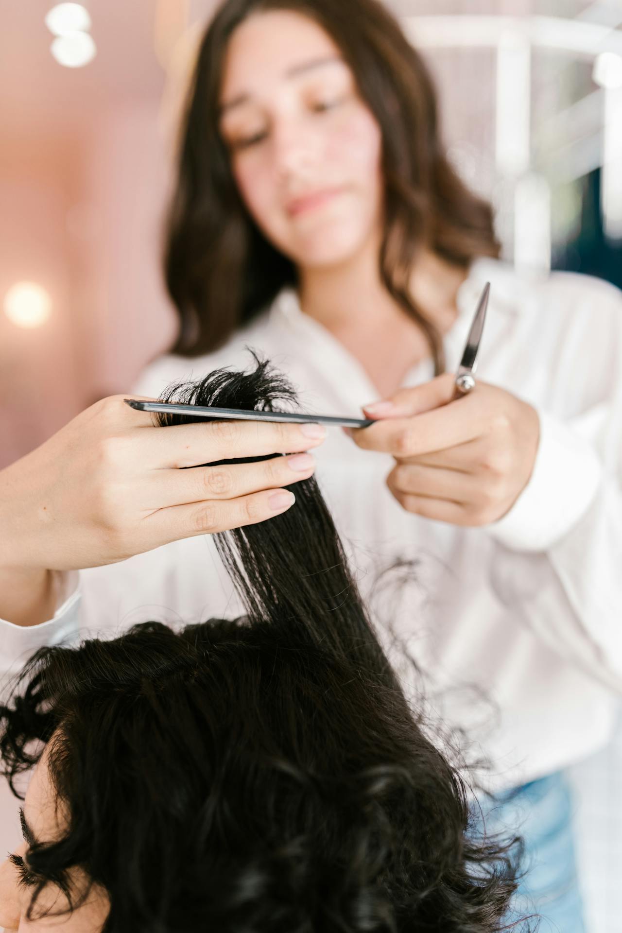 Un styliste coupe les cheveux d'une femme dans un salon | Source : Pexels