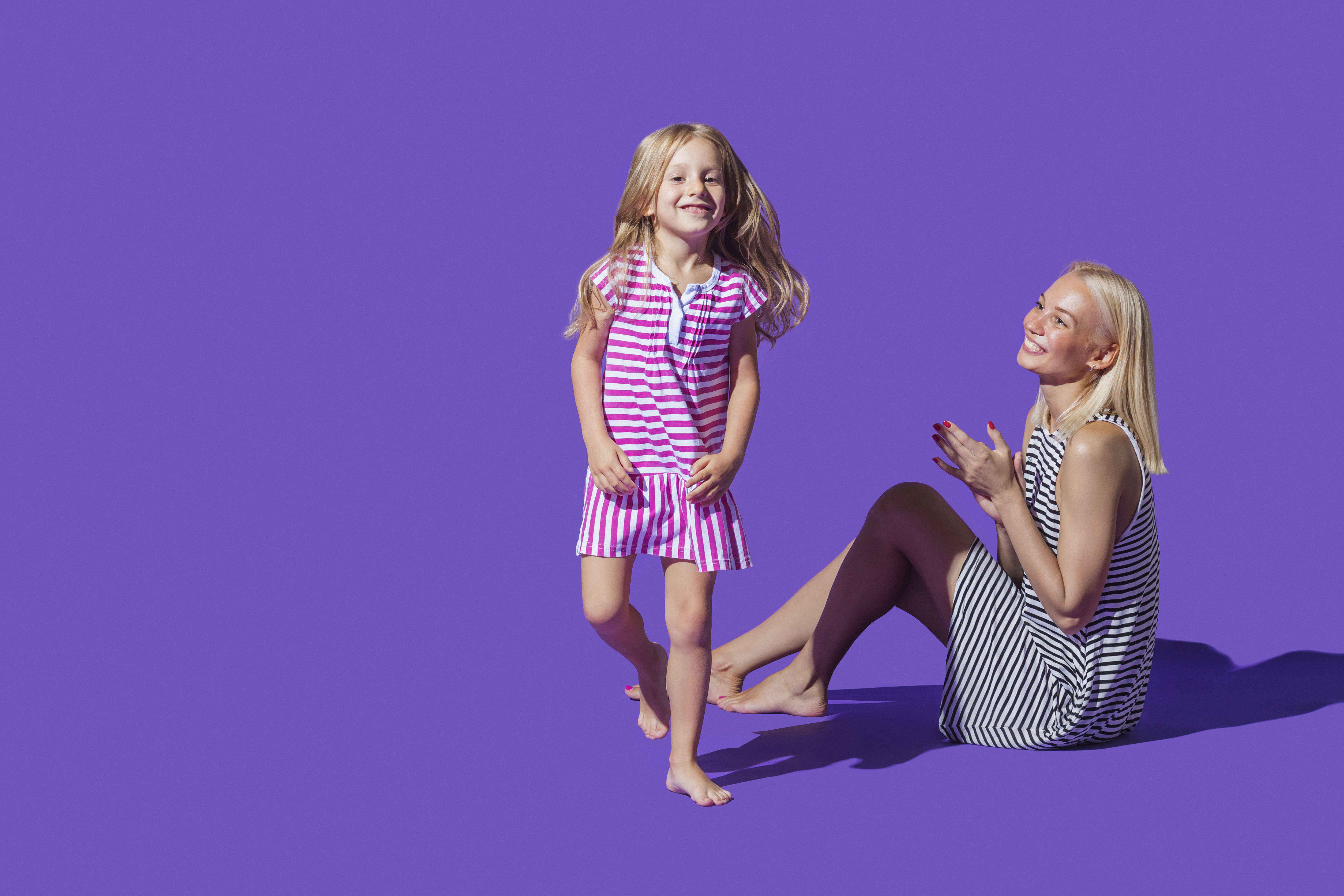 Une mère et sa fille en robes rayées sur fond violet | Source : Getty Images