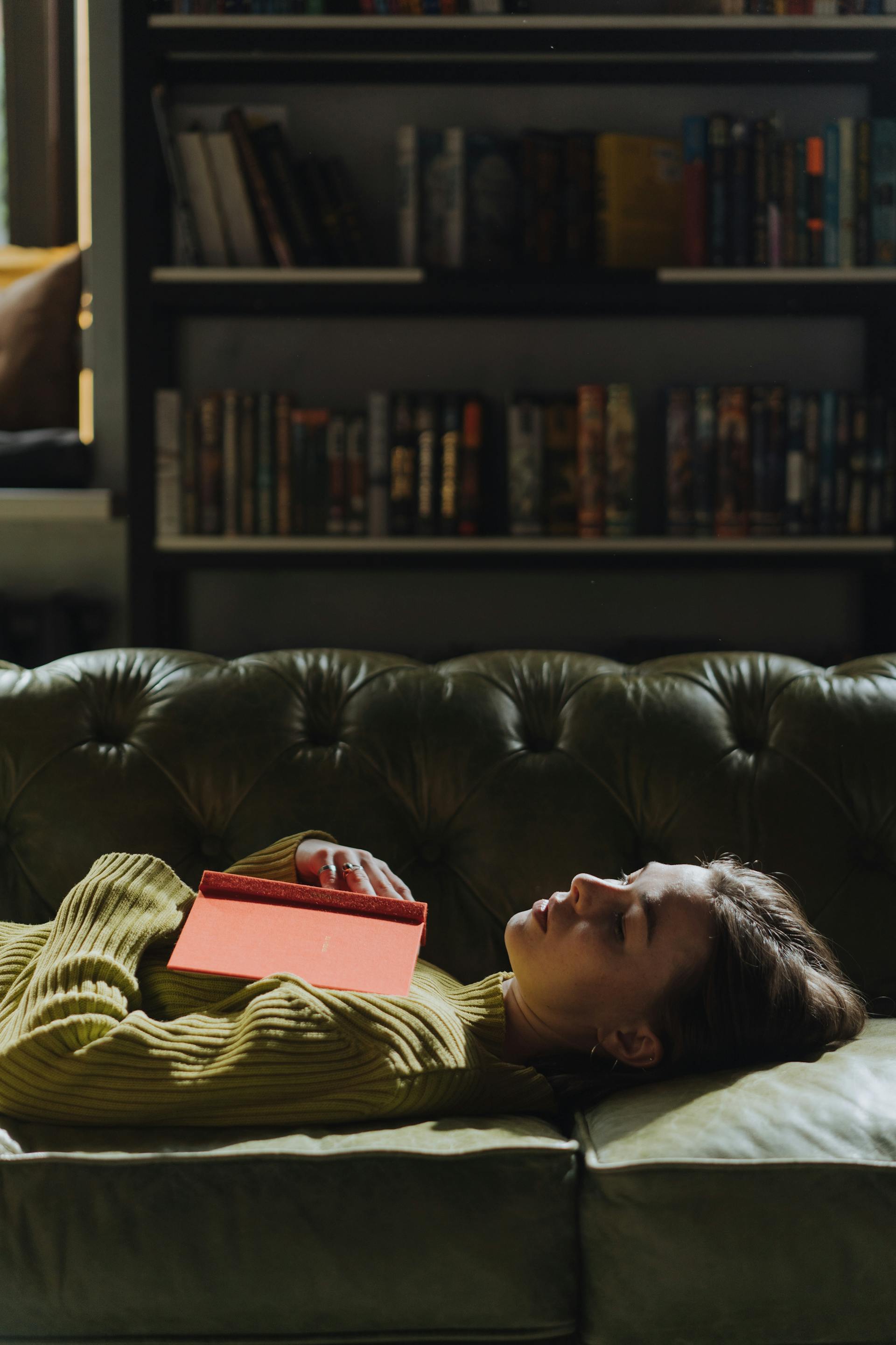 Une femme allongée sur un canapé avec un livre | Source : Pexels