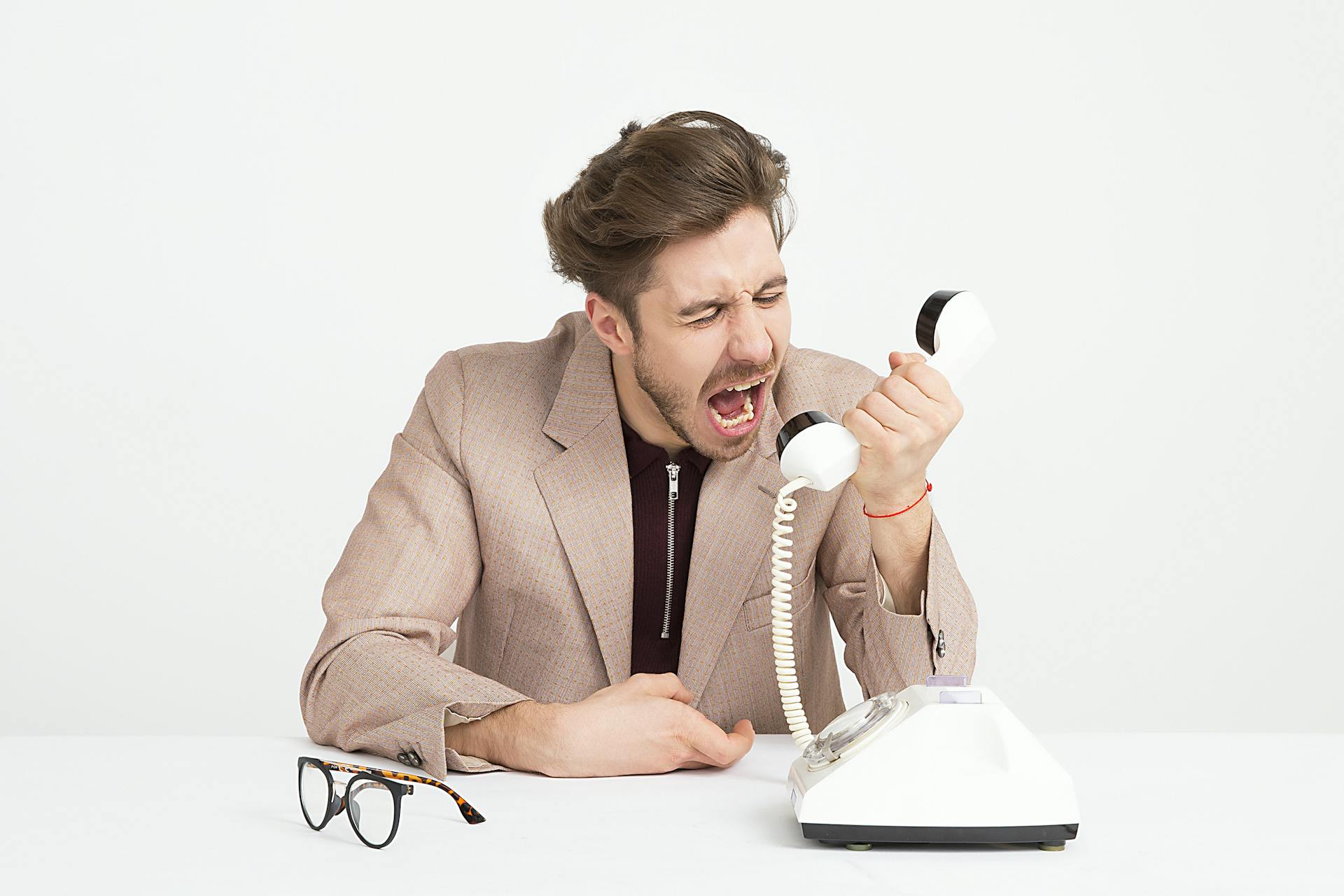 Un homme qui crie en tenant un appareil téléphonique noir et blanc | Source : Pexels