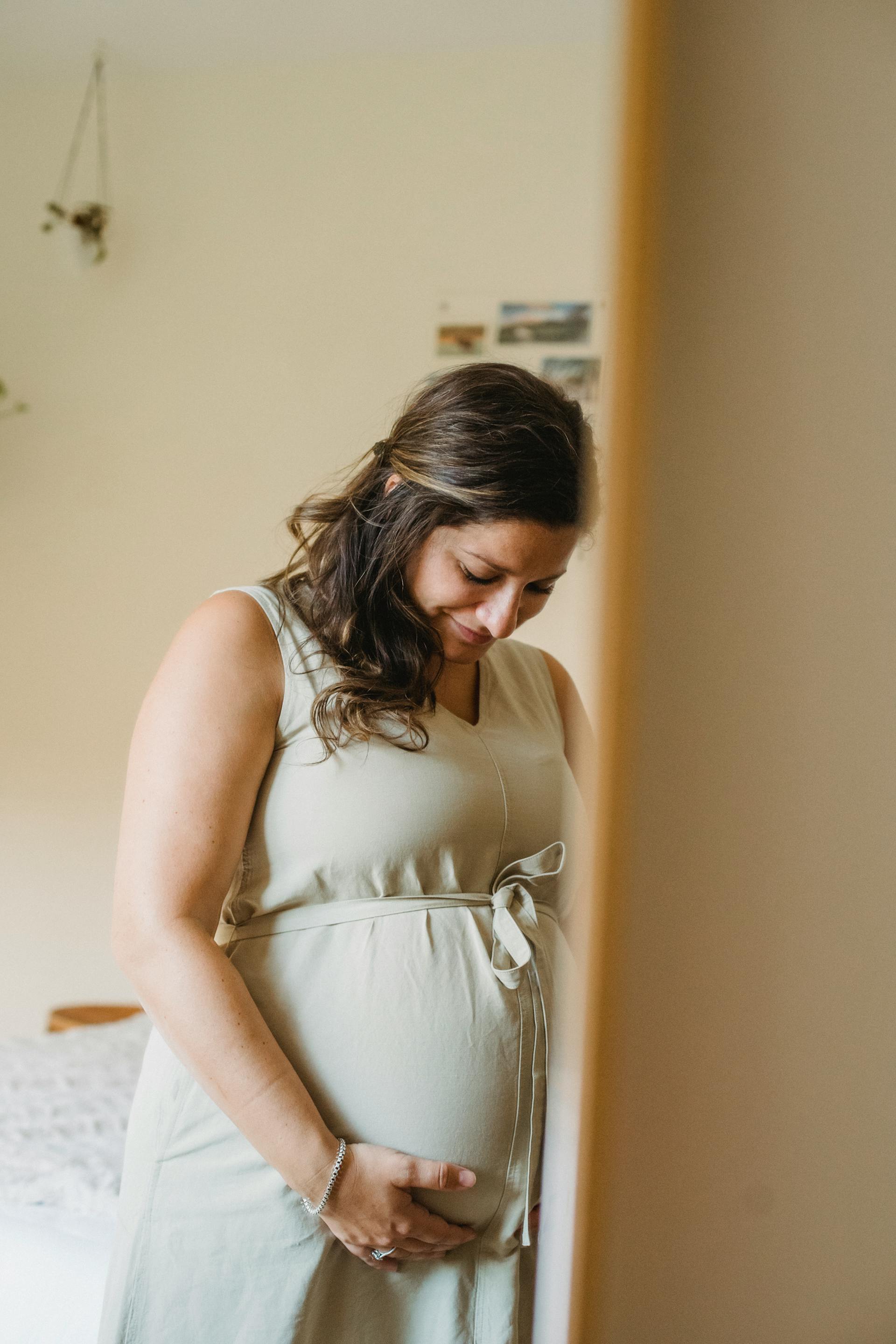Une femme qui sourit à son ventre de femme enceinte | Source : Pexels