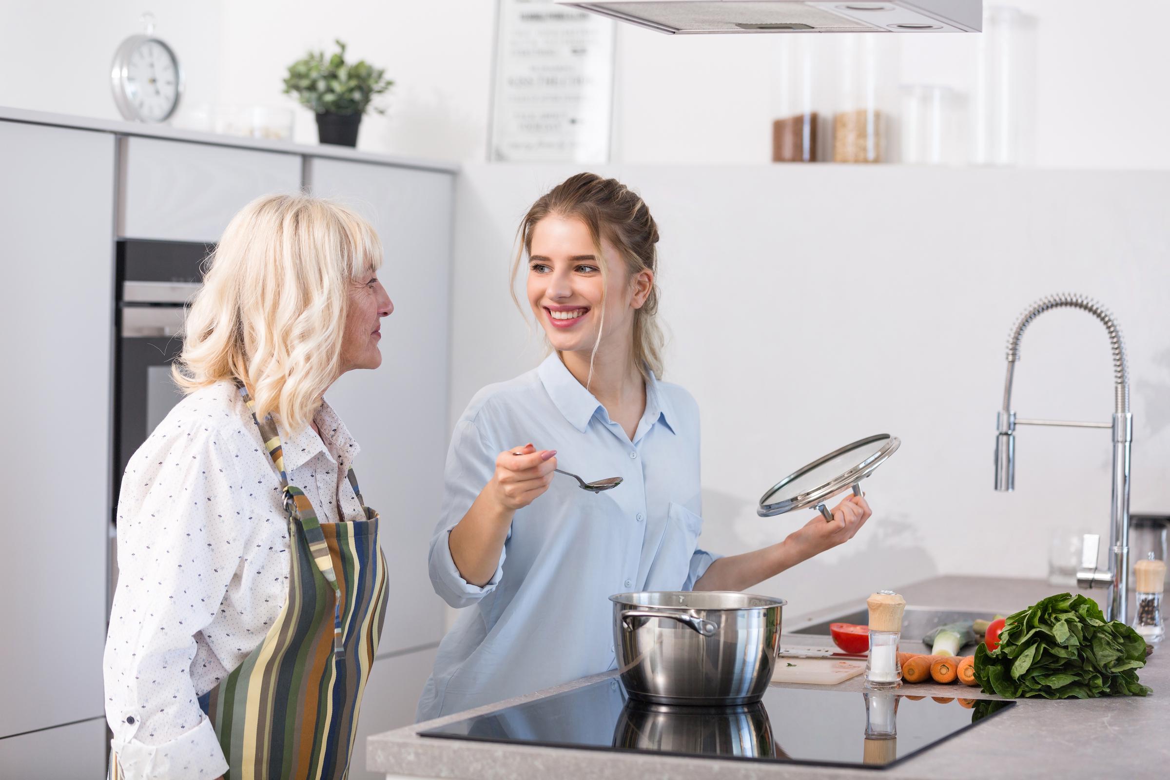 Une femme souriante qui parle à une femme plus âgée dans la cuisine | Source : Freepik