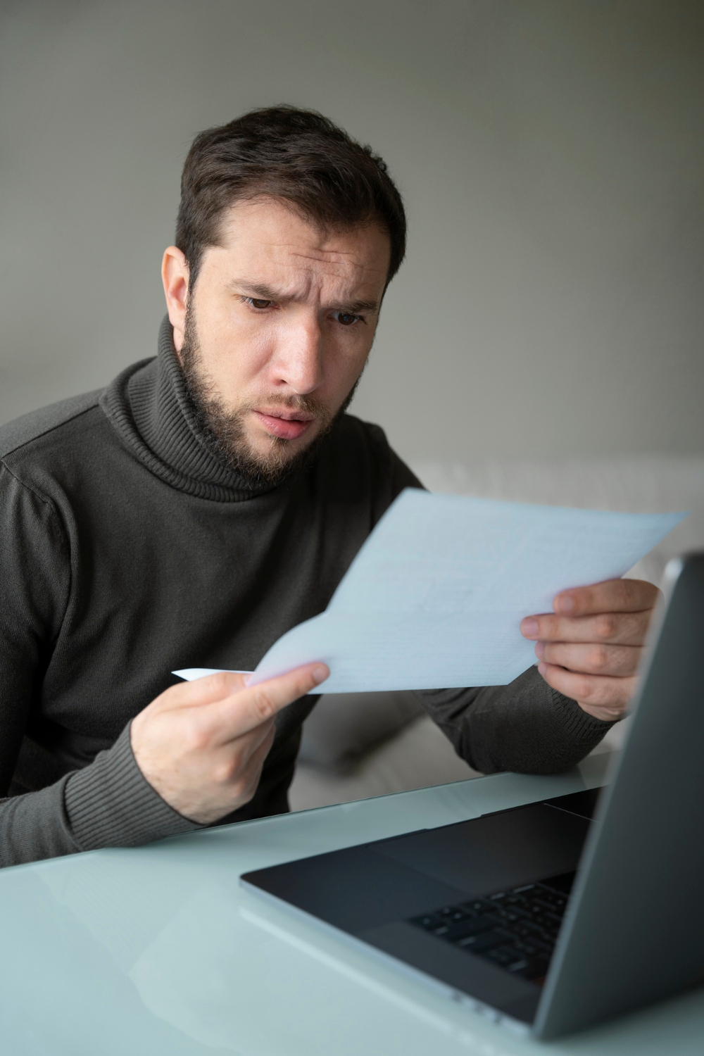 Un homme stupéfait qui regarde une feuille de papier | Source : Freepik
