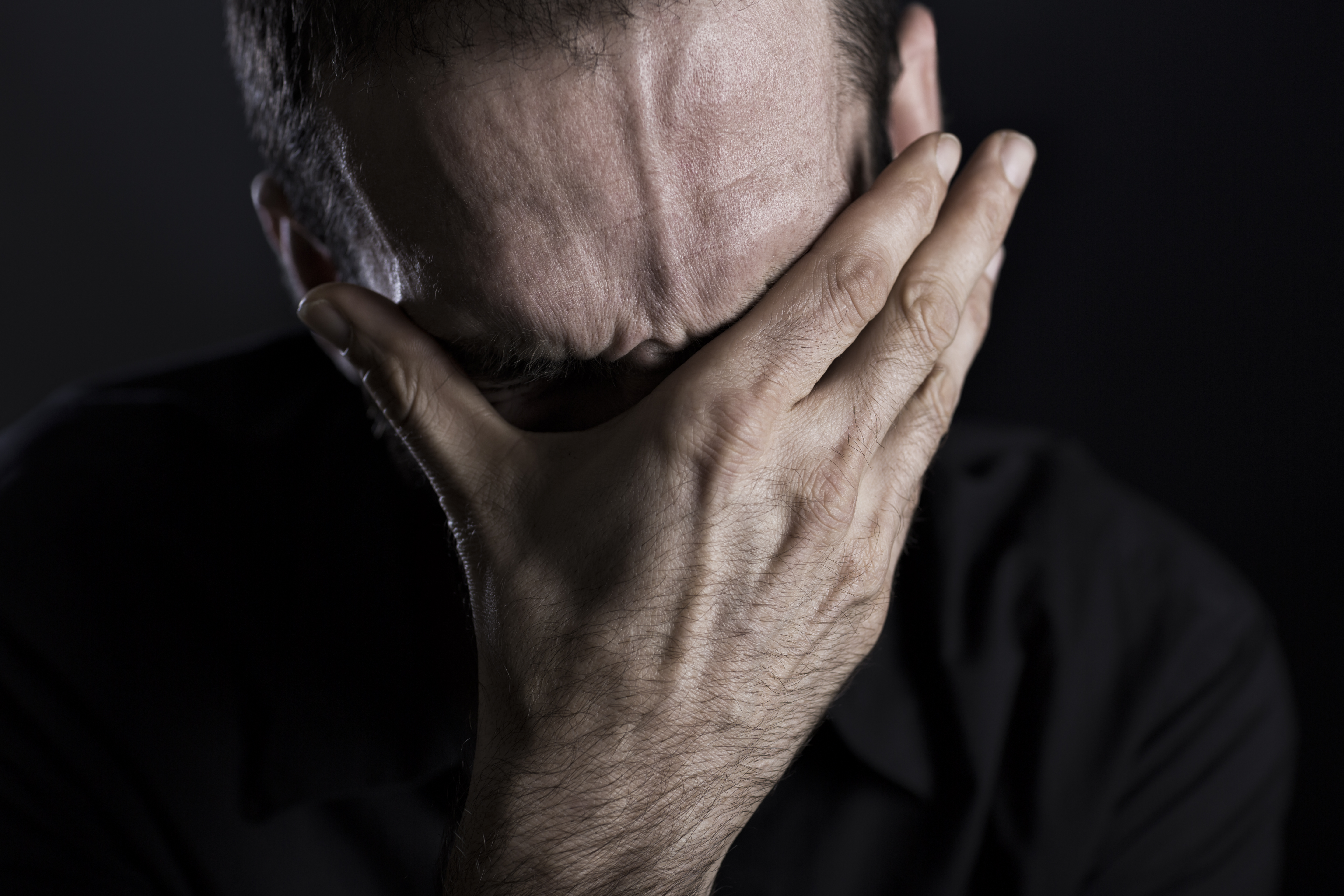 Un homme triste se couvrant le visage | Source : Getty Images