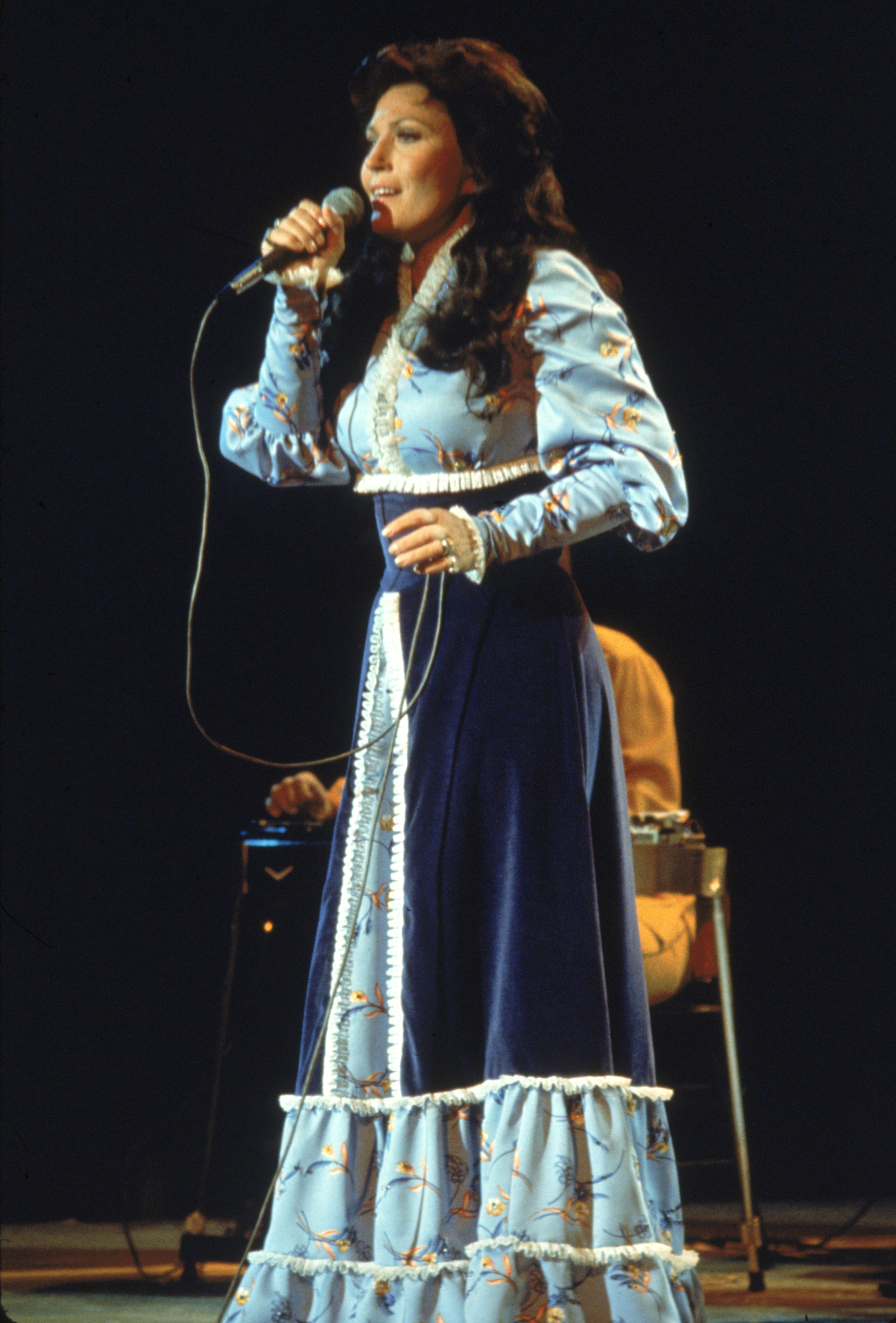Loretta Lynn se produit sur scène, vêtue d'une longue robe, en 1980. | Source : Getty Images