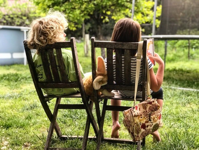 Deux enfants assissent sur une chaise entrain de lire un livre | Photo : Unsplash
