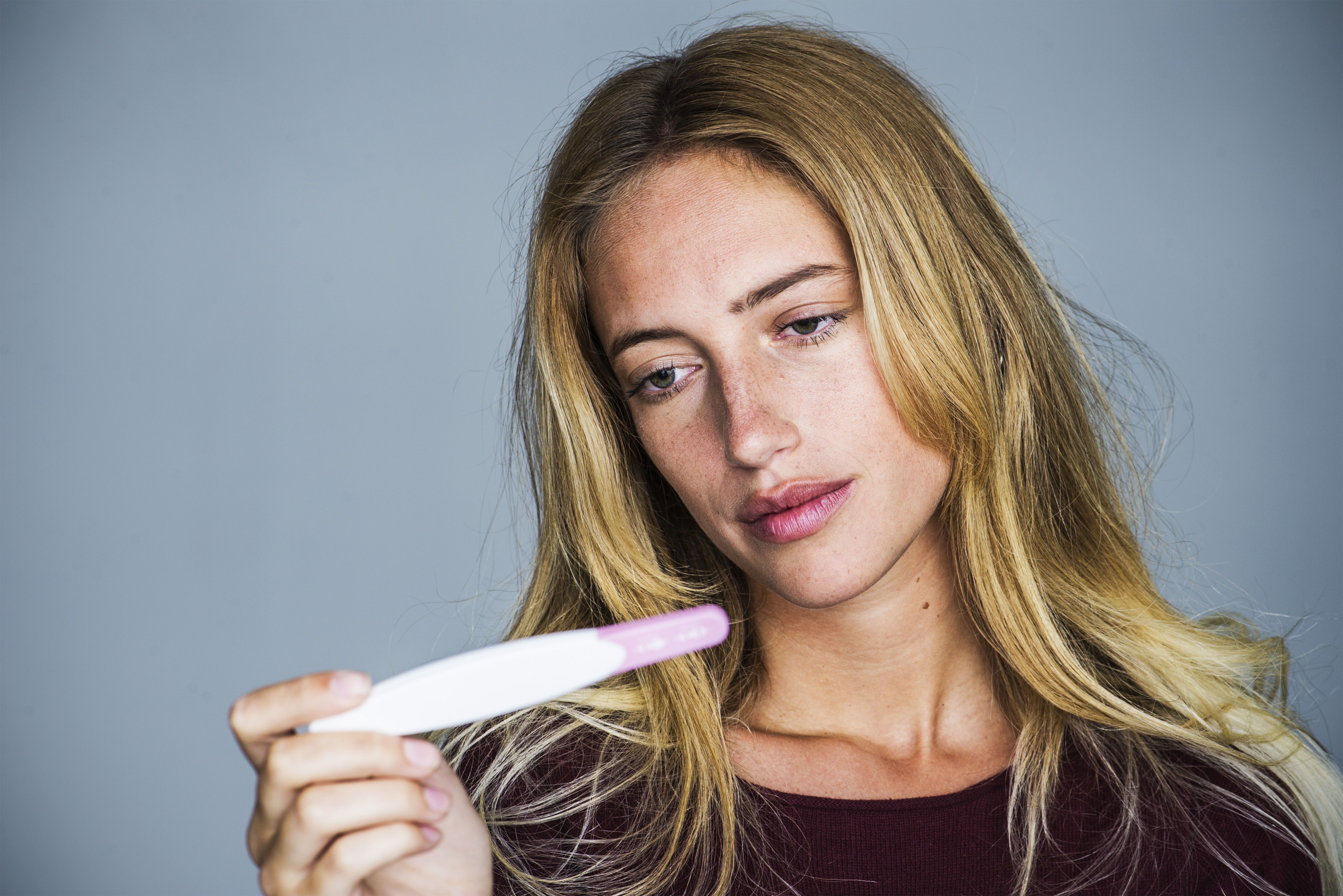 Jeune femme regardant un test de grossesse avec une expression déçue | Source : Getty Images