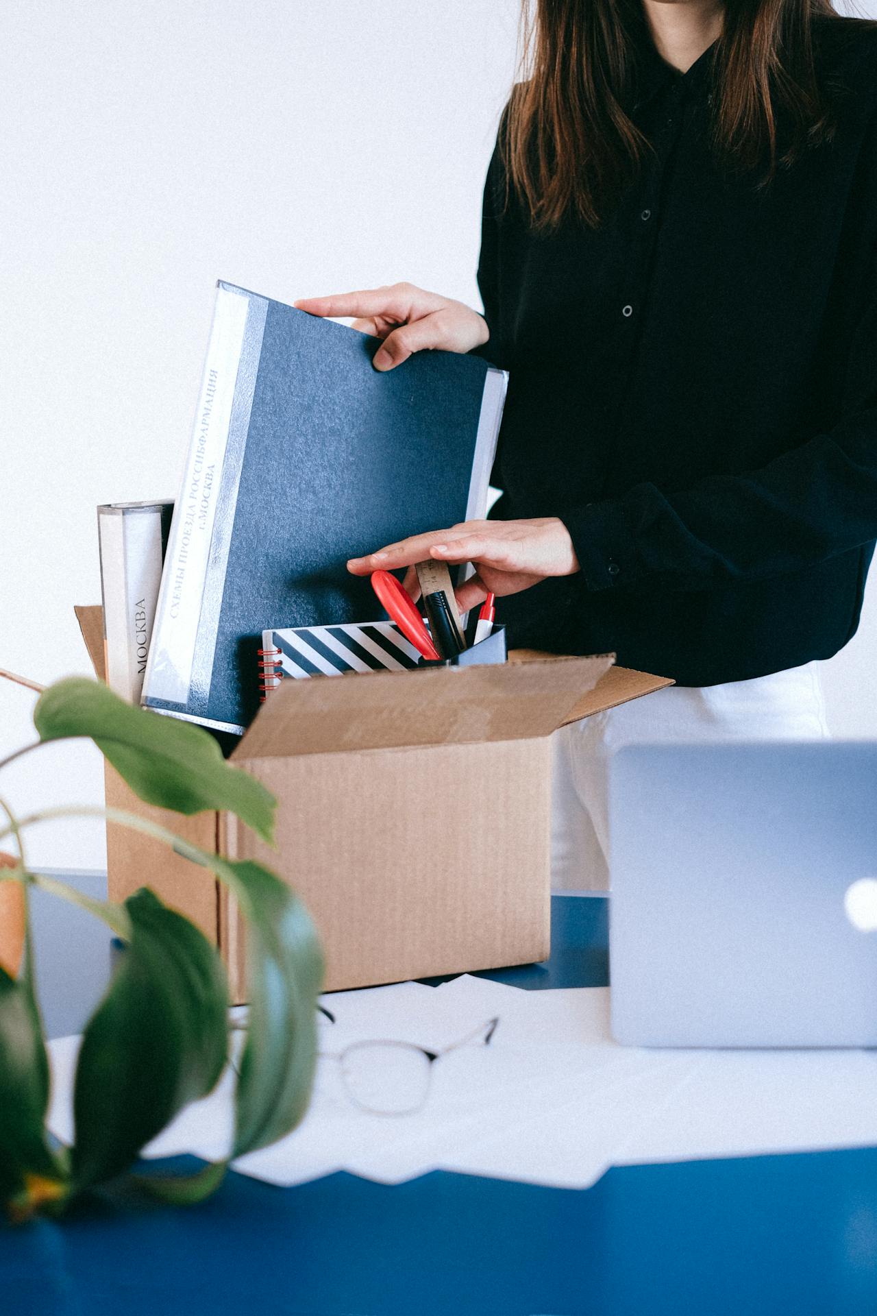 Une femme qui organise des fournitures de bureau dans une boîte | Source : Pexels