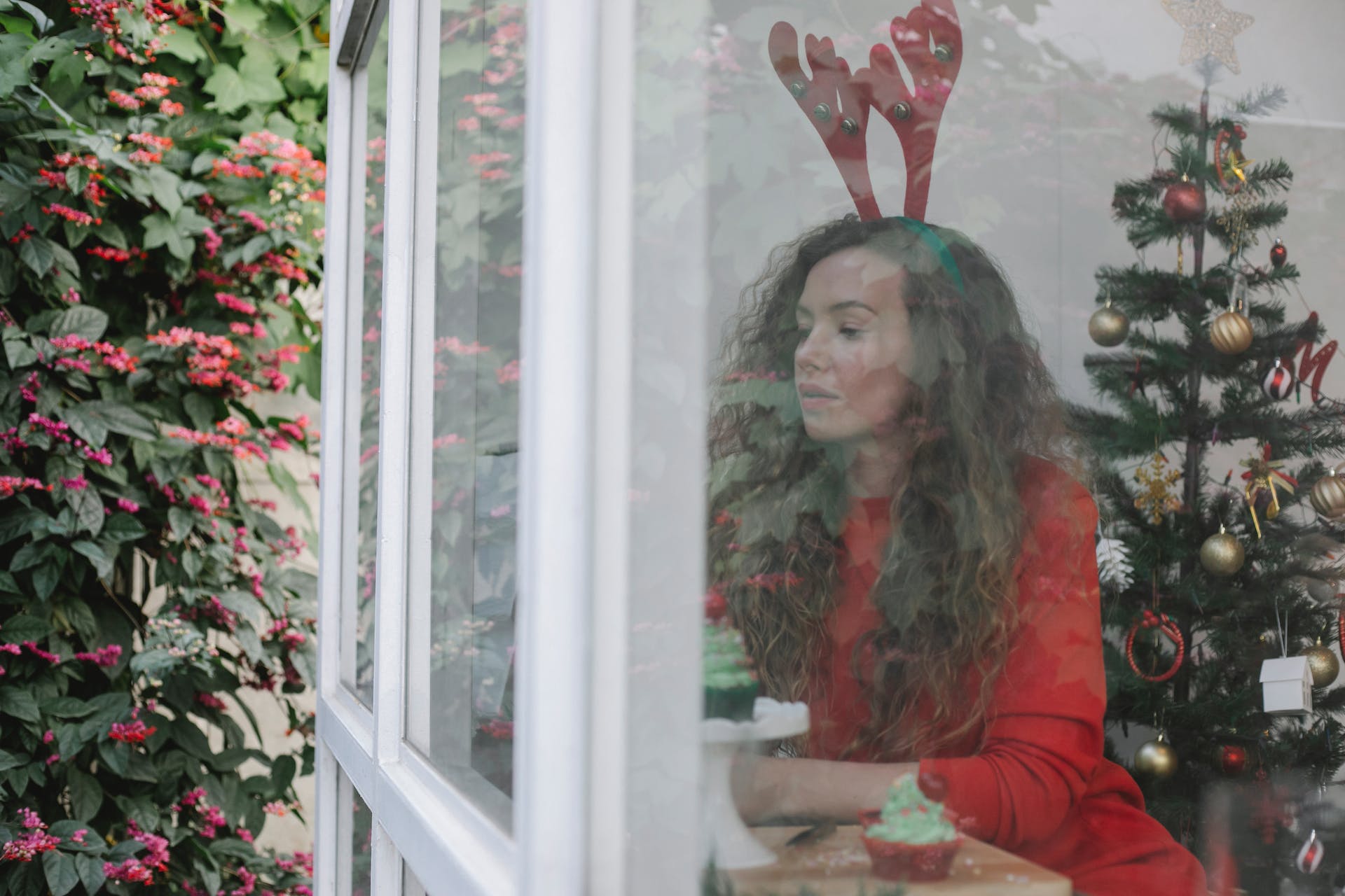 Une femme habillée en renne regarde dehors depuis sa fenêtre pendant la période de Noël | Source : Pexels