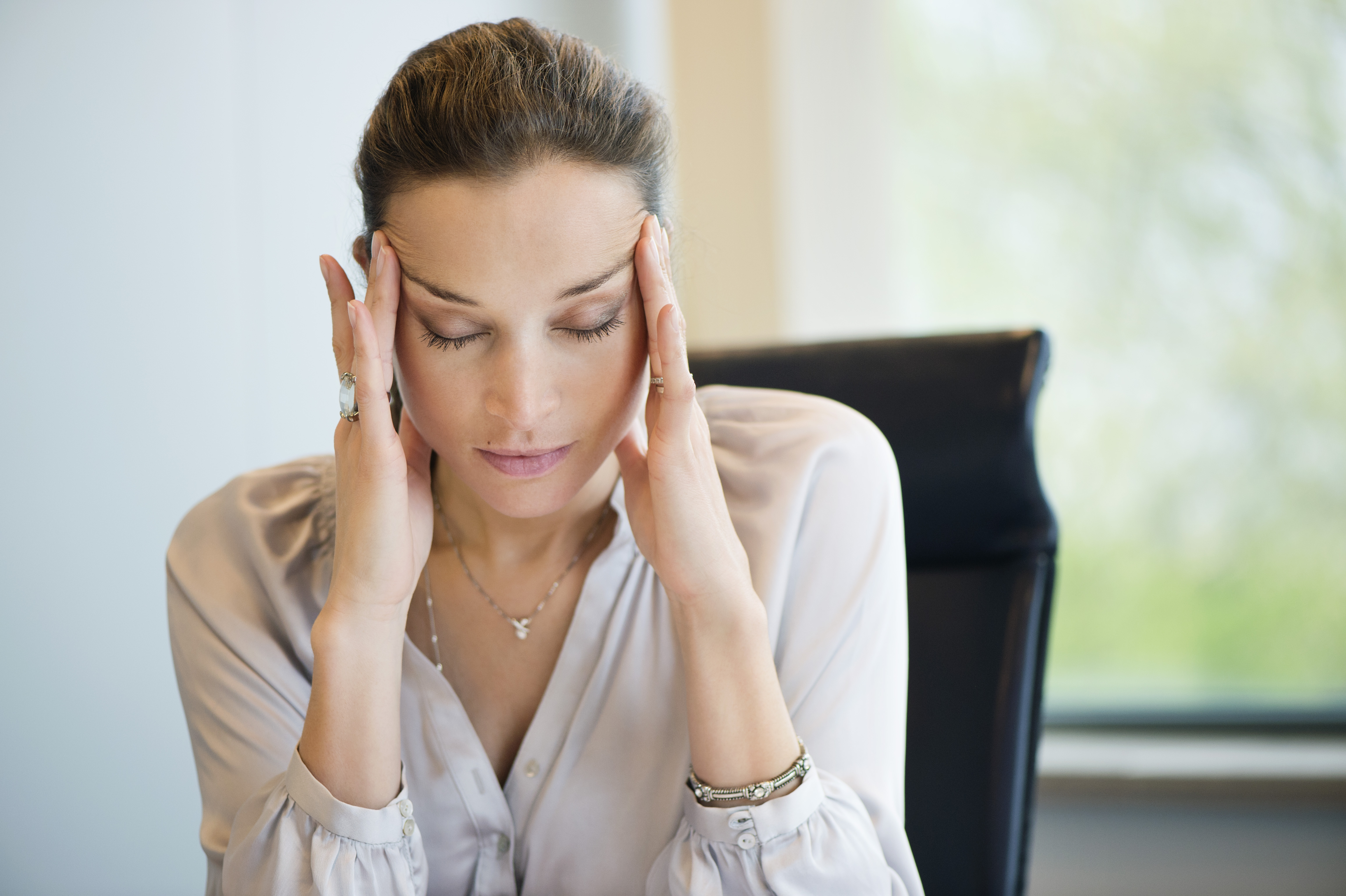 Femme souffrant d'un mal de tête alors qu'elle travaille dans un bureau | Source : Getty Images